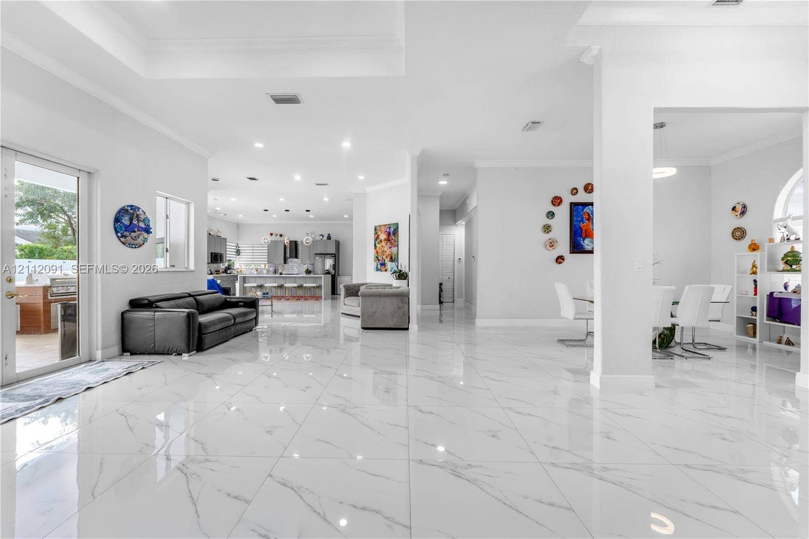 29481 SW 193rd Court, Homestead, FL 33030 Open-concept main living area featuring large-format polished tile flooring, recessed lighting, tray ceilings, and a glass-paneled door leading to an outdoor space
