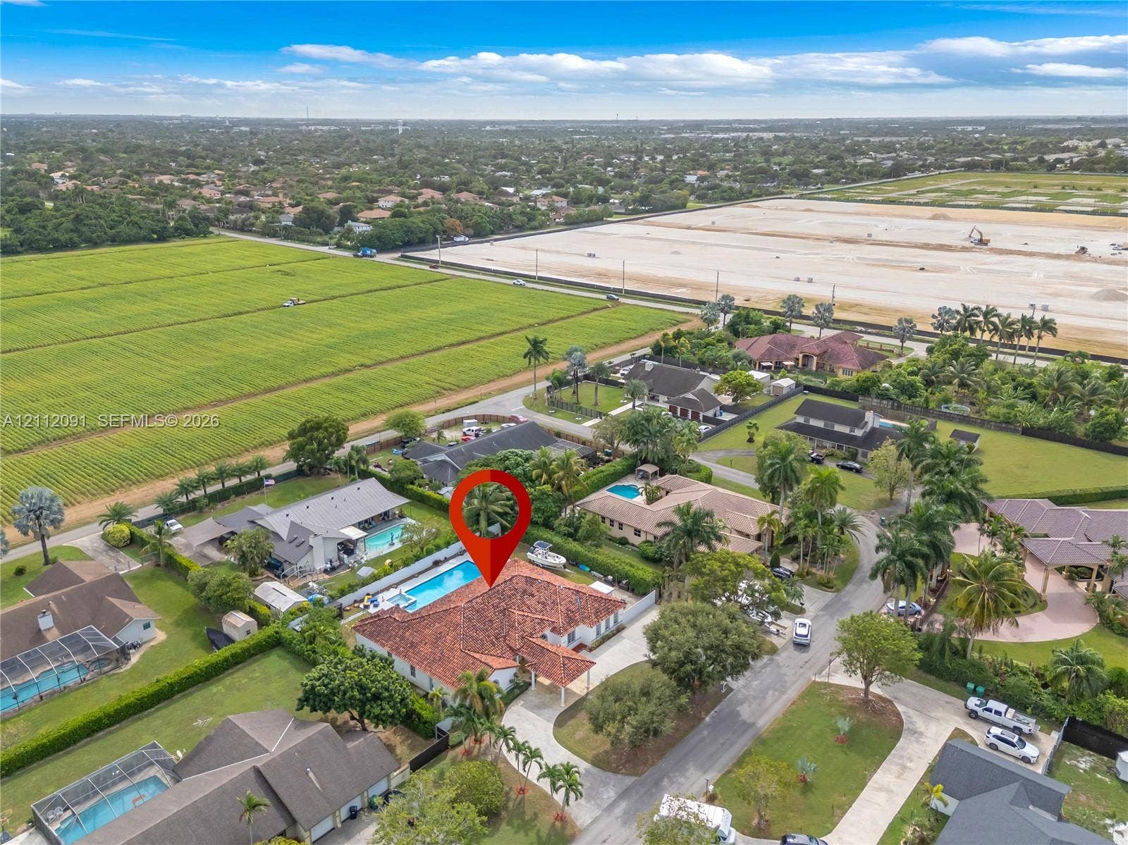 29481 SW 193rd Court, Homestead, FL 33030 Aerial perspective of a property featuring a multi-hipped tile roof, an expansive paved driveway, and a private rear swimming pool