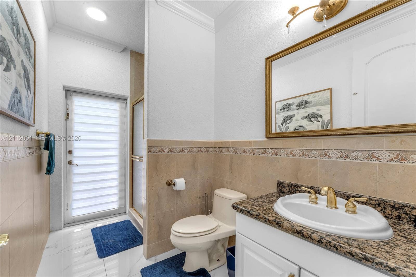 29481 SW 193rd Court, Homestead, FL 33030 Bathroom featuring stone-finish countertop, undermount sink with gold-tone hardware, decorative tiled wall accent, glass-enclosed shower, and opaque-paned exterior door
