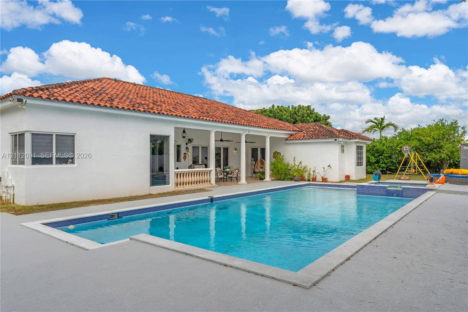 29481 SW 193rd Court, Homestead, FL 33030 Single-story residence featuring a tile roof, covered patio with structural columns, and an integrated in-ground pool with an attached spa