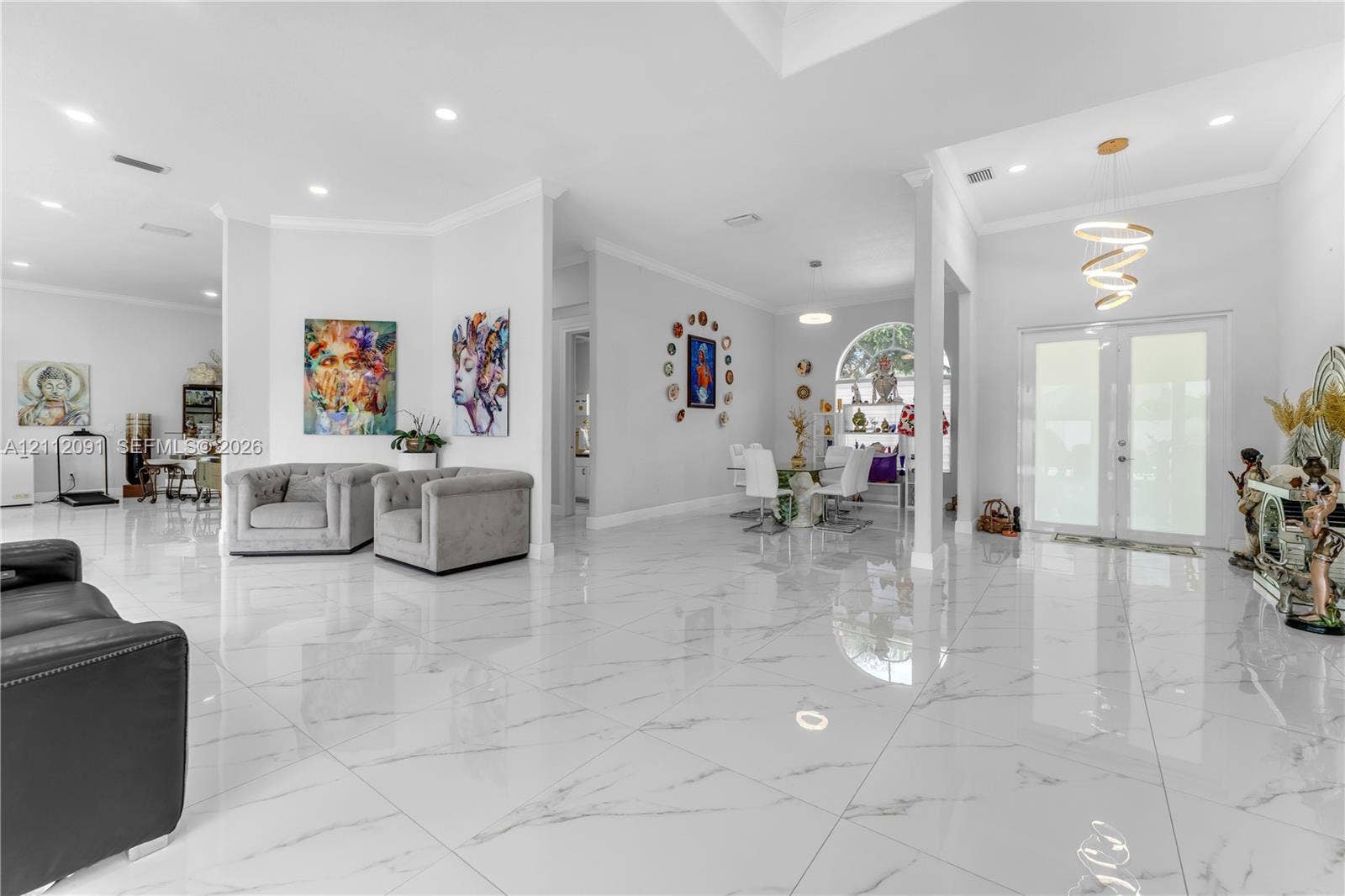29481 SW 193rd Court, Homestead, FL 33030 Open-concept interior featuring large-format stone-finish tile flooring, recessed ceiling lighting, a modern spiral chandelier, and an arched window
