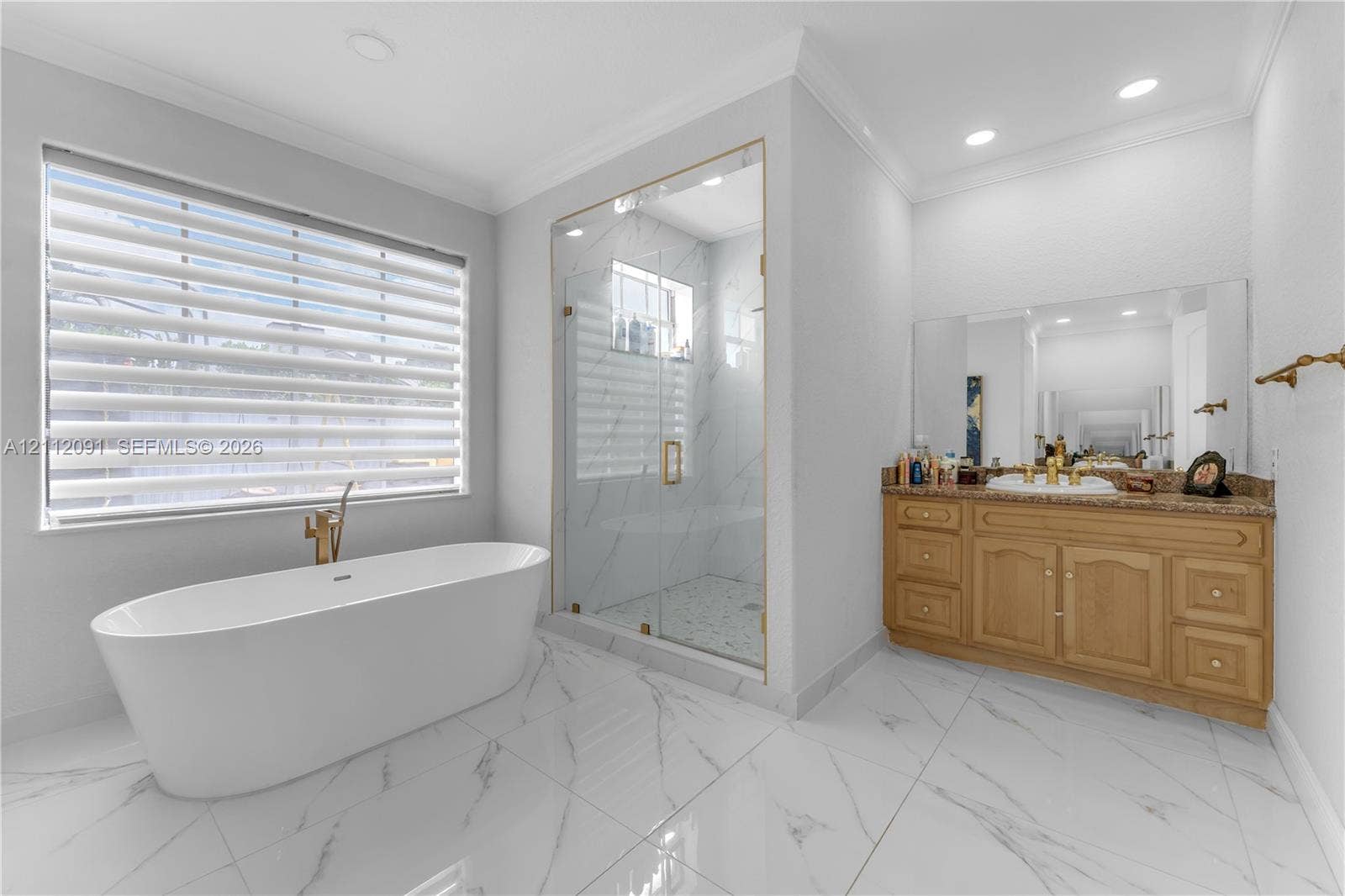 29481 SW 193rd Court, Homestead, FL 33030 Freestanding soaking tub with gold-tone fixtures, walk-in glass-enclosed shower with tiled surround, stone-finish vanity countertop, and polished tile flooring