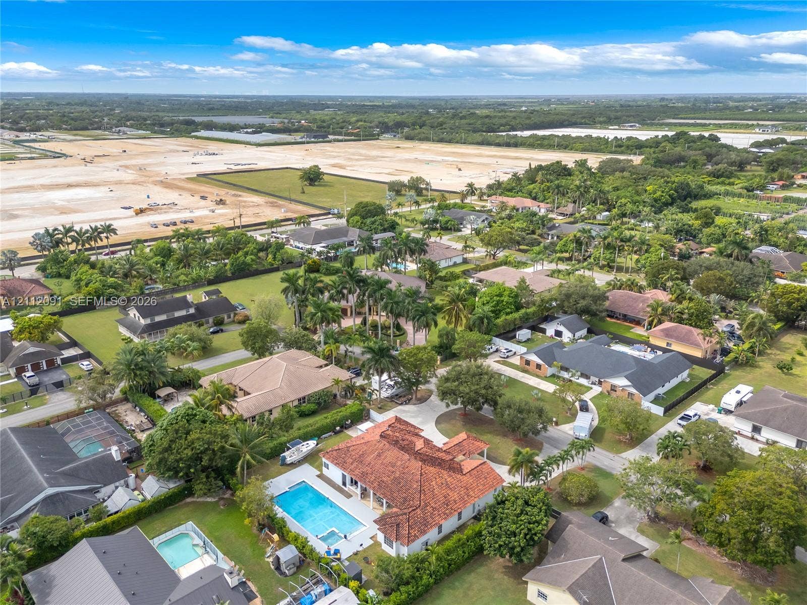 29481 SW 193rd Court, Homestead, FL 33030 Aerial perspective featuring a terracotta-tiled roof, rectangular swimming pool, integrated spa, and concrete driveway on a landscaped lot