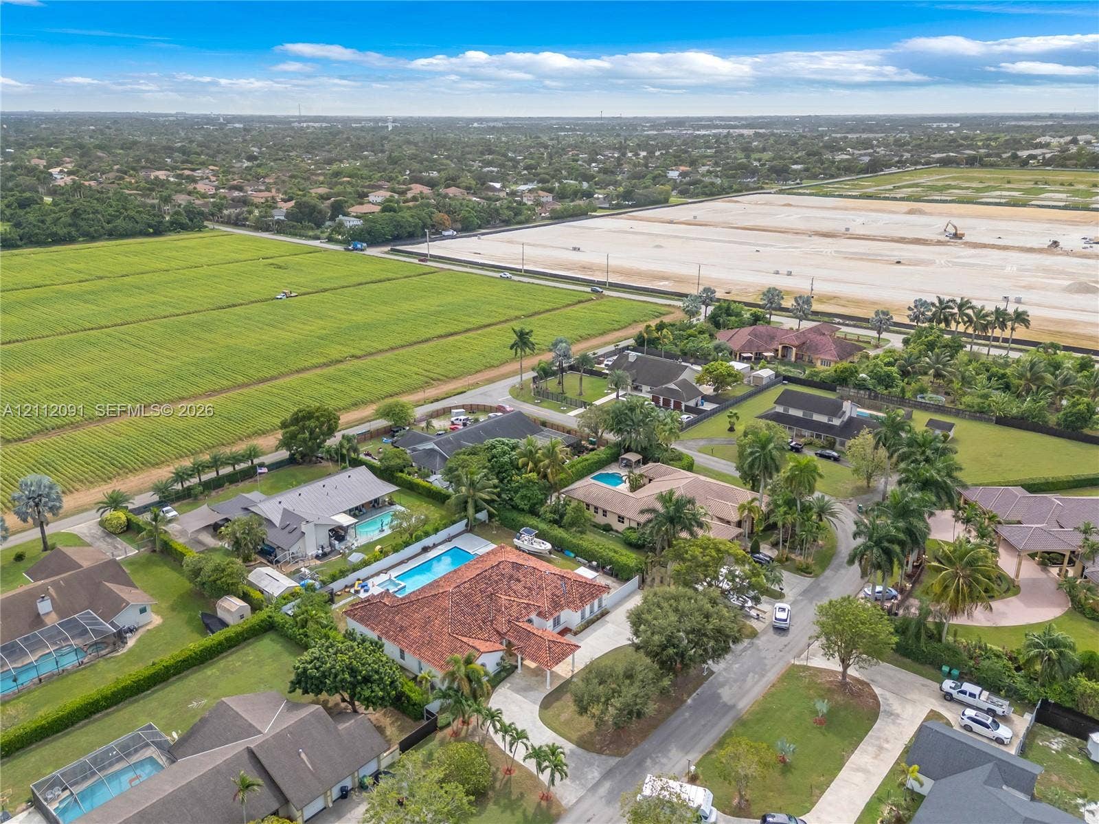 29481 SW 193rd Court, Homestead, FL 33030 Aerial perspective of a sprawling property featuring a multi-gabled terracotta tile roof, a rectangular swimming pool, an expansive paver driveway, and mature landscaping