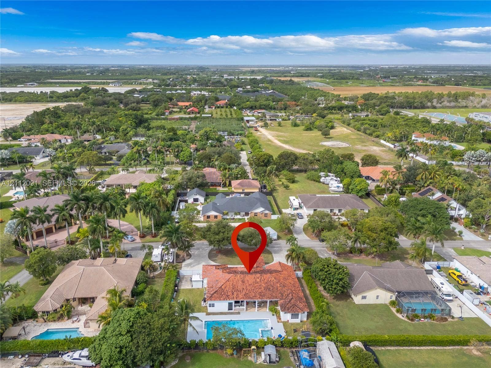 29481 SW 193rd Court, Homestead, FL 33030 Aerial perspective of a residential property featuring a tile roof, an in-ground swimming pool with an attached spa, and a concrete driveway