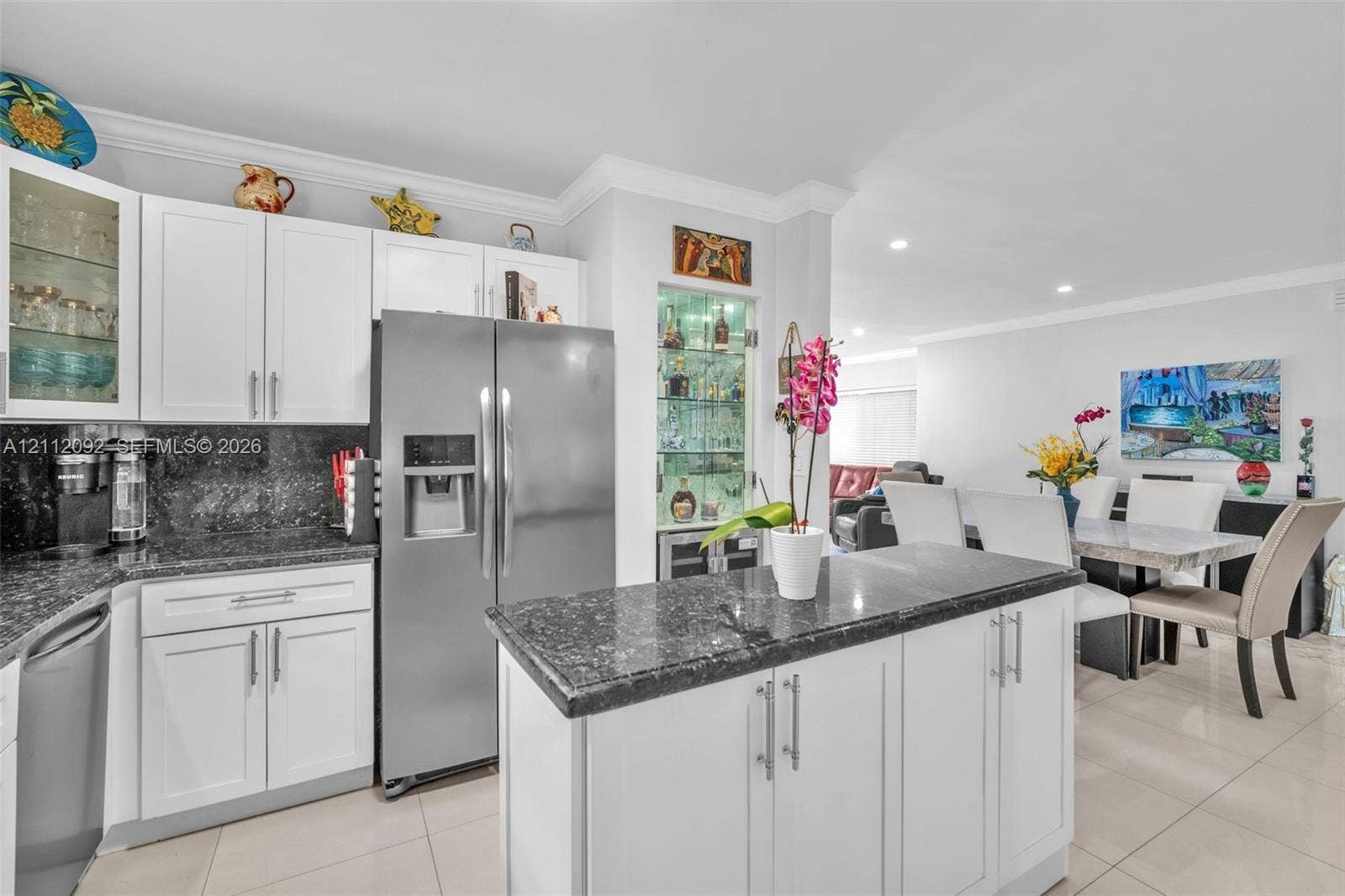 419 Sevilla Avenue, Coral Gables, FL 33134 Kitchen featuring white shaker-style cabinetry, dark stone countertops, a central island, recessed lighting, and a built-in glass-front display cabinet