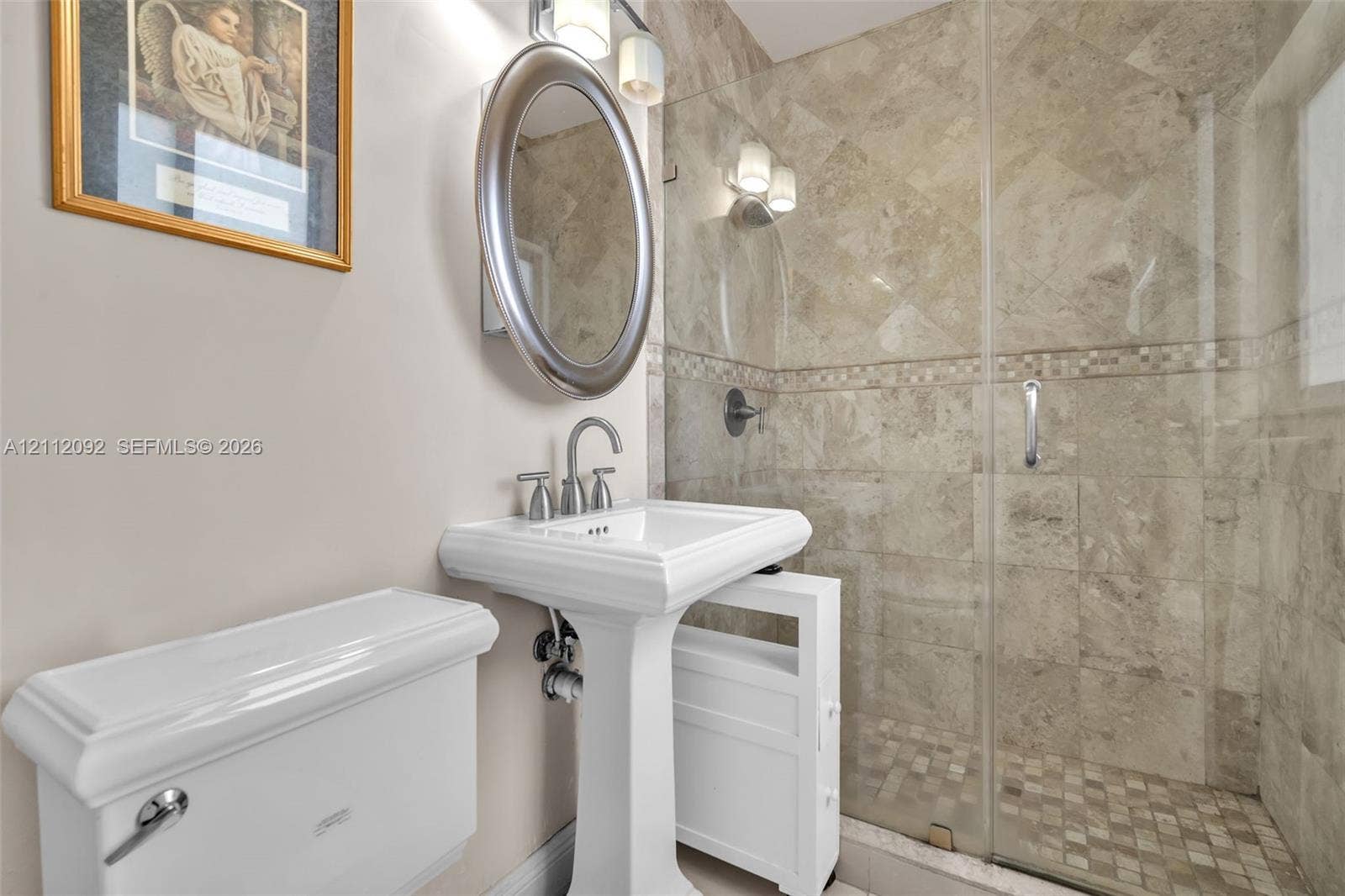 419 Sevilla Avenue, Coral Gables, FL 33134 Bathroom featuring a pedestal sink, oval wall-mounted mirror, glass-enclosed shower with stone-tile surround, and mosaic tile shower flooring