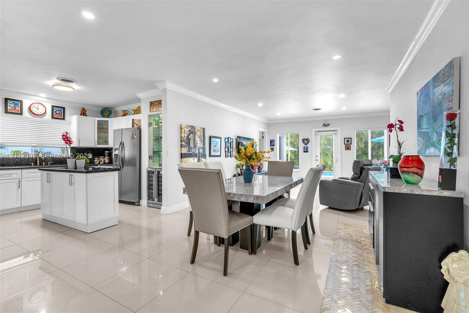 419 Sevilla Avenue, Coral Gables, FL 33134 Open-concept interior featuring large-format tile flooring, recessed lighting, and a kitchen with white cabinetry, a center island with dark countertops, and a built-in wine cooler
