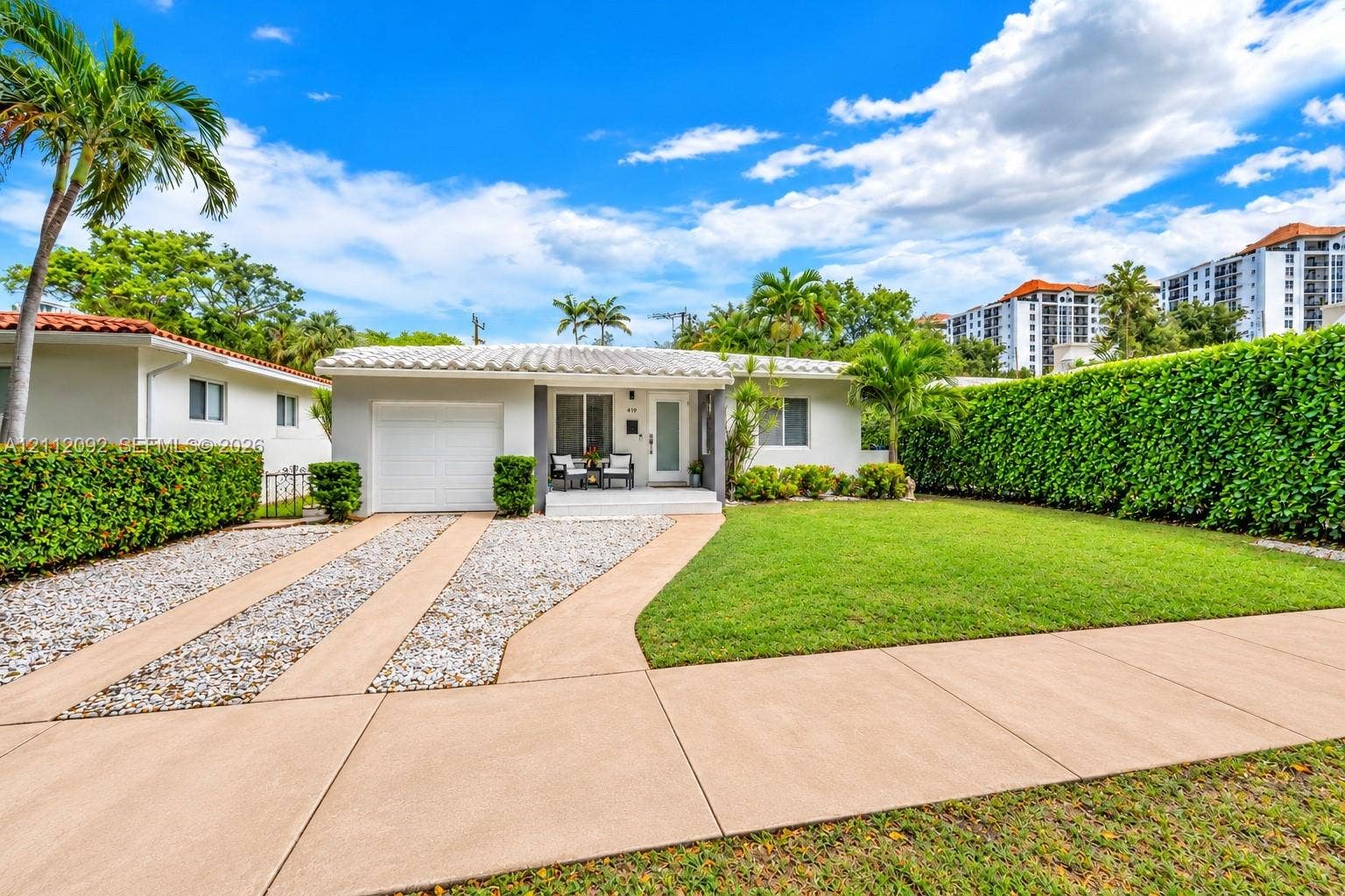 419 Sevilla Avenue, Coral Gables, FL 33134 Single-story residence featuring a barrel tile roof, concrete driveway, attached garage, and manicured lawn