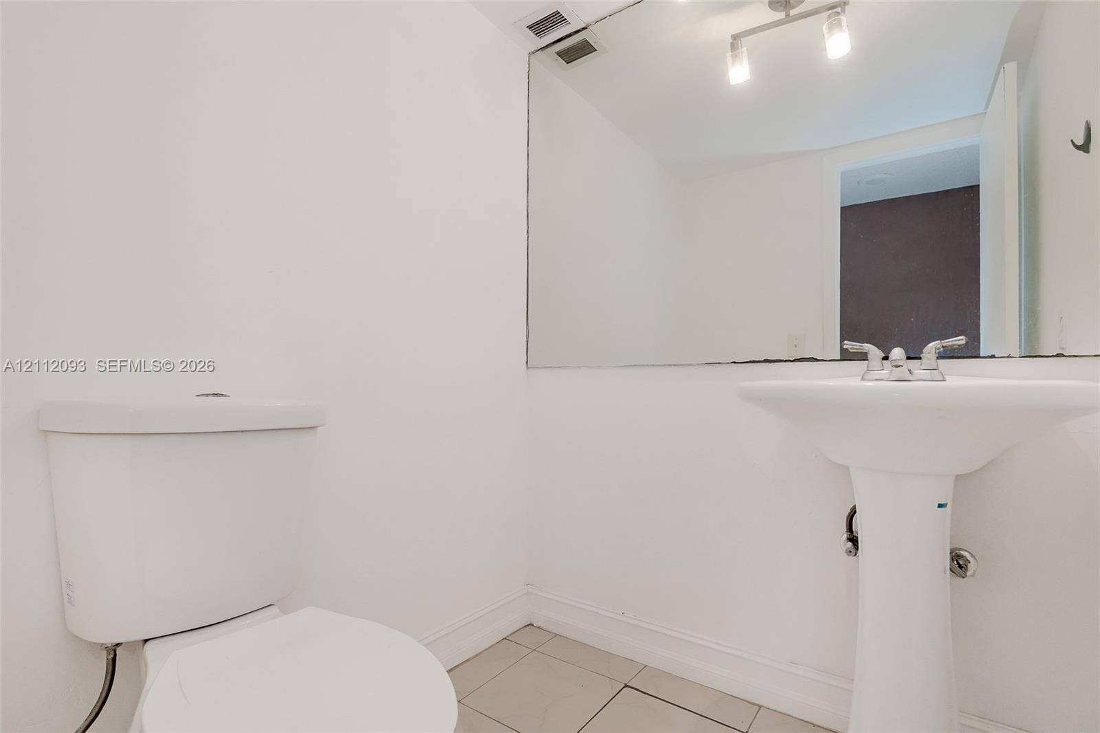 2750 NE 183rd Street, #1612, Aventura, FL 33160 Bathroom featuring a pedestal sink, dual-handle chrome faucet, wall-spanning vanity mirror, multi-light bar fixture, and tile flooring