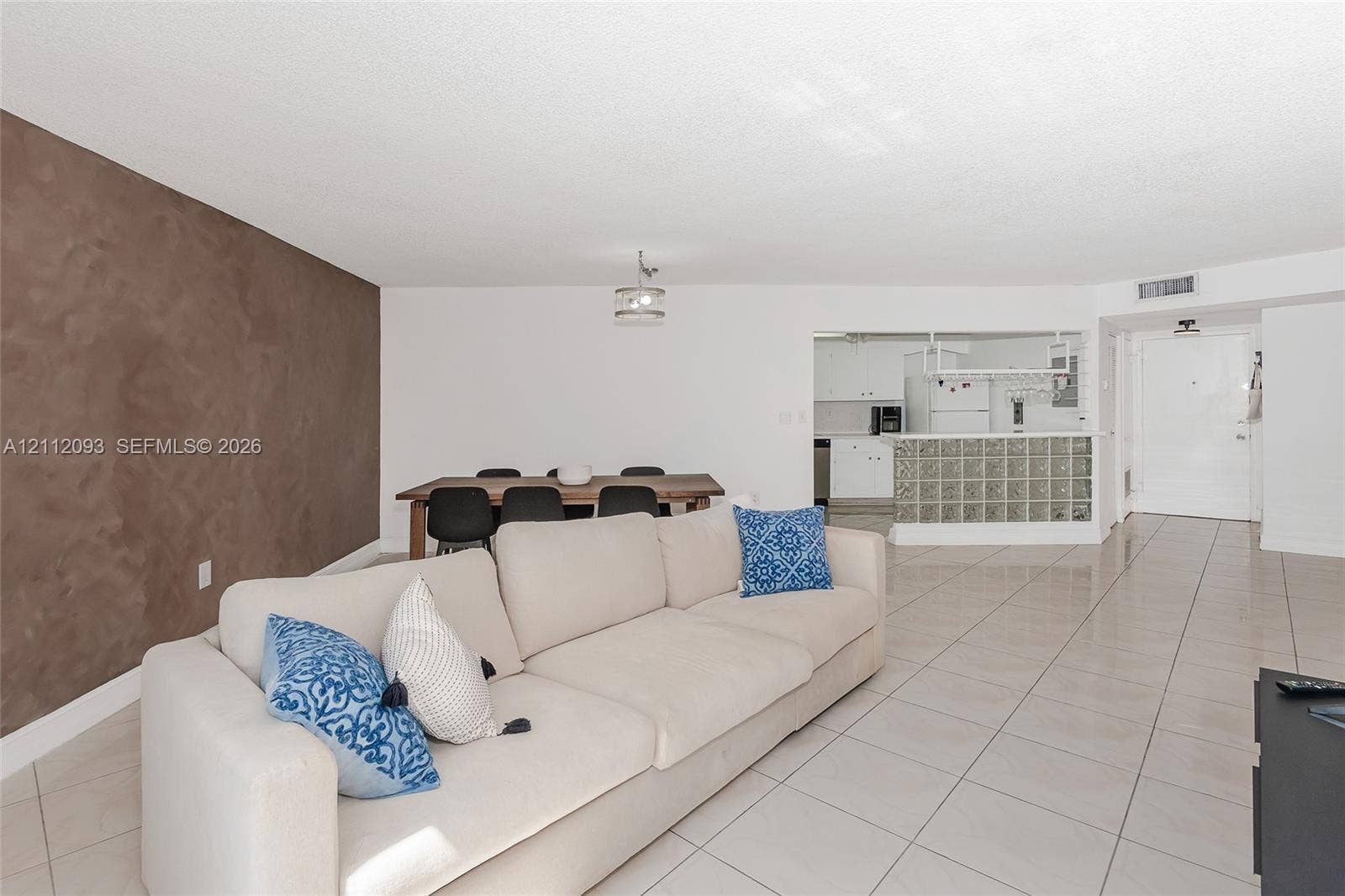2750 NE 183rd Street, #1612, Aventura, FL 33160 Neutral-toned tile flooring, accent wall with textured finish, glass block kitchen partition, and overhead semi-flush mount lighting