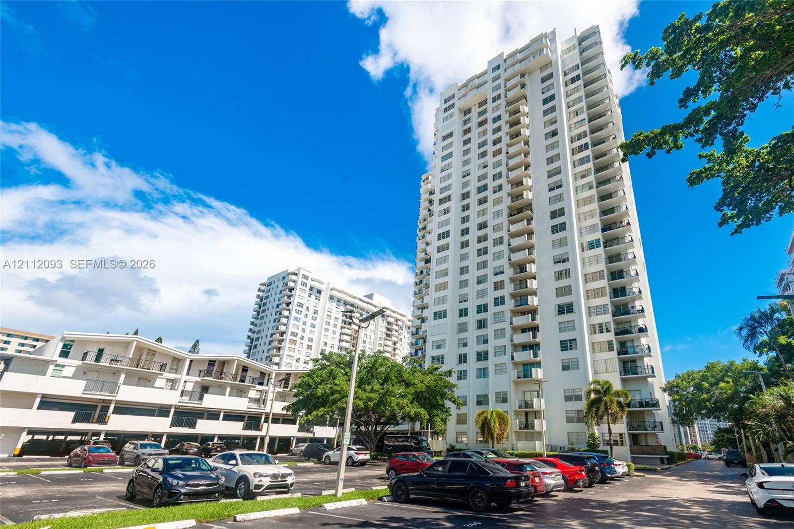 2750 NE 183rd Street, #1612, Aventura, FL 33160 High-rise residential tower featuring white stucco exterior, multiple stacked balconies, and paved surface parking