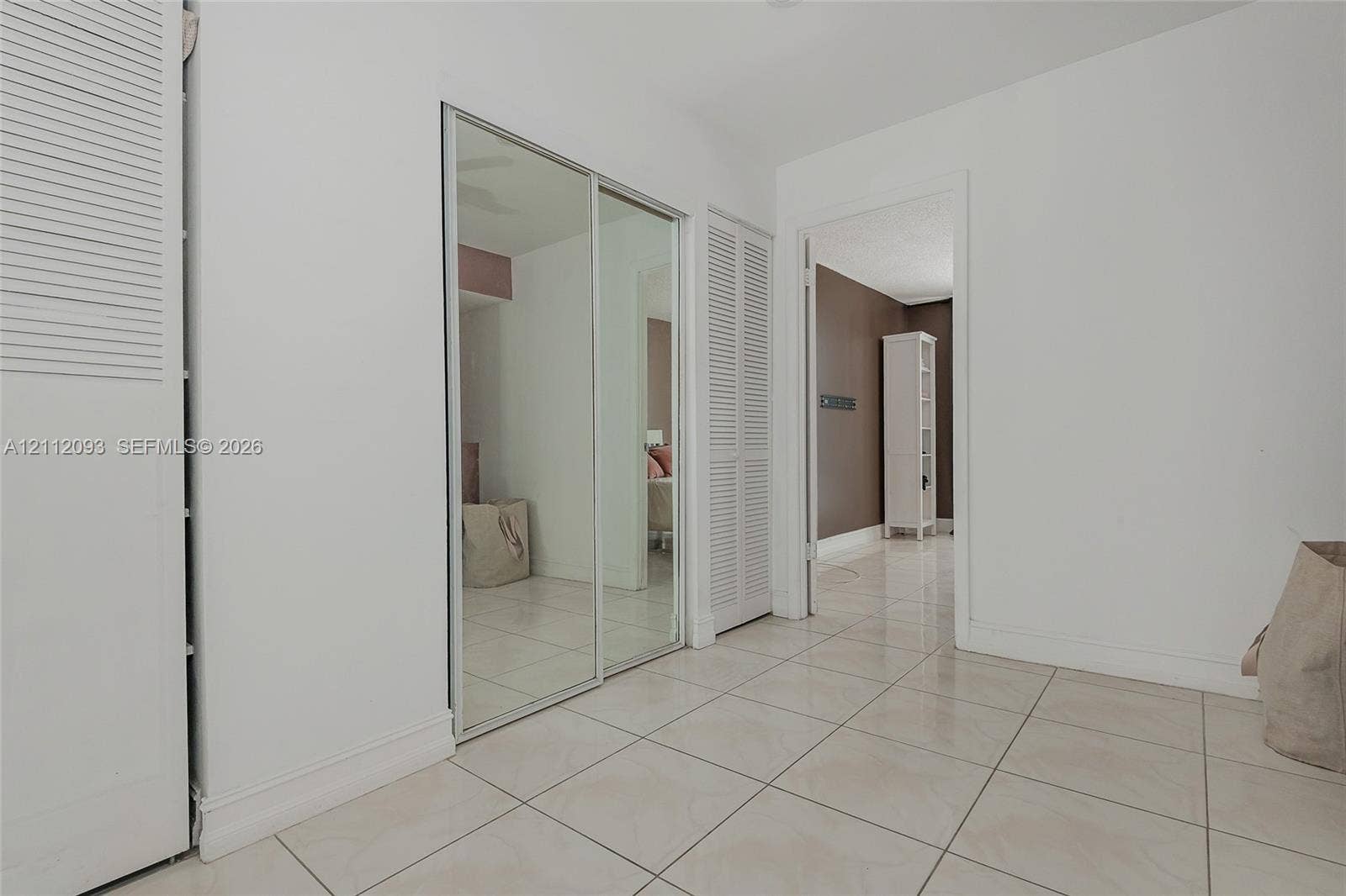 2750 NE 183rd Street, #1612, Aventura, FL 33160 Tiled flooring, floor-to-ceiling mirrored sliding closet doors, and bi-fold closet doors