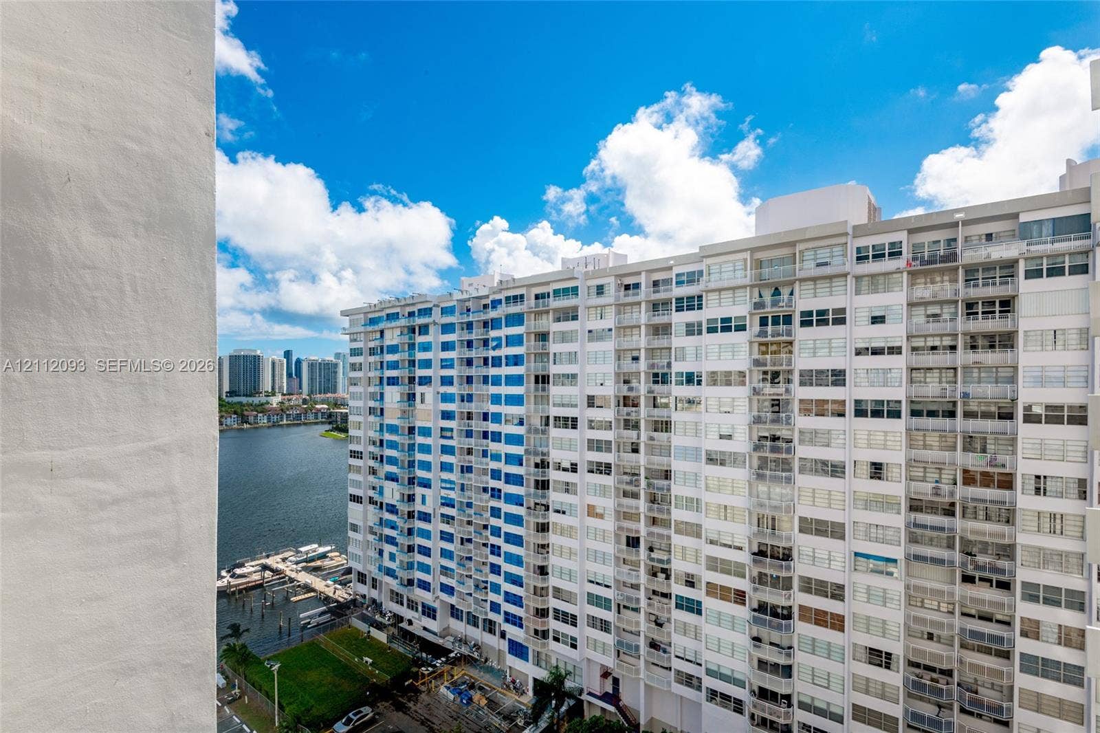 2750 NE 183rd Street, #1612, Aventura, FL 33160 High-rise exterior featuring integrated balconies, floor-to-ceiling windows, and white masonry cladding, overlooking a coastal waterway and dock area