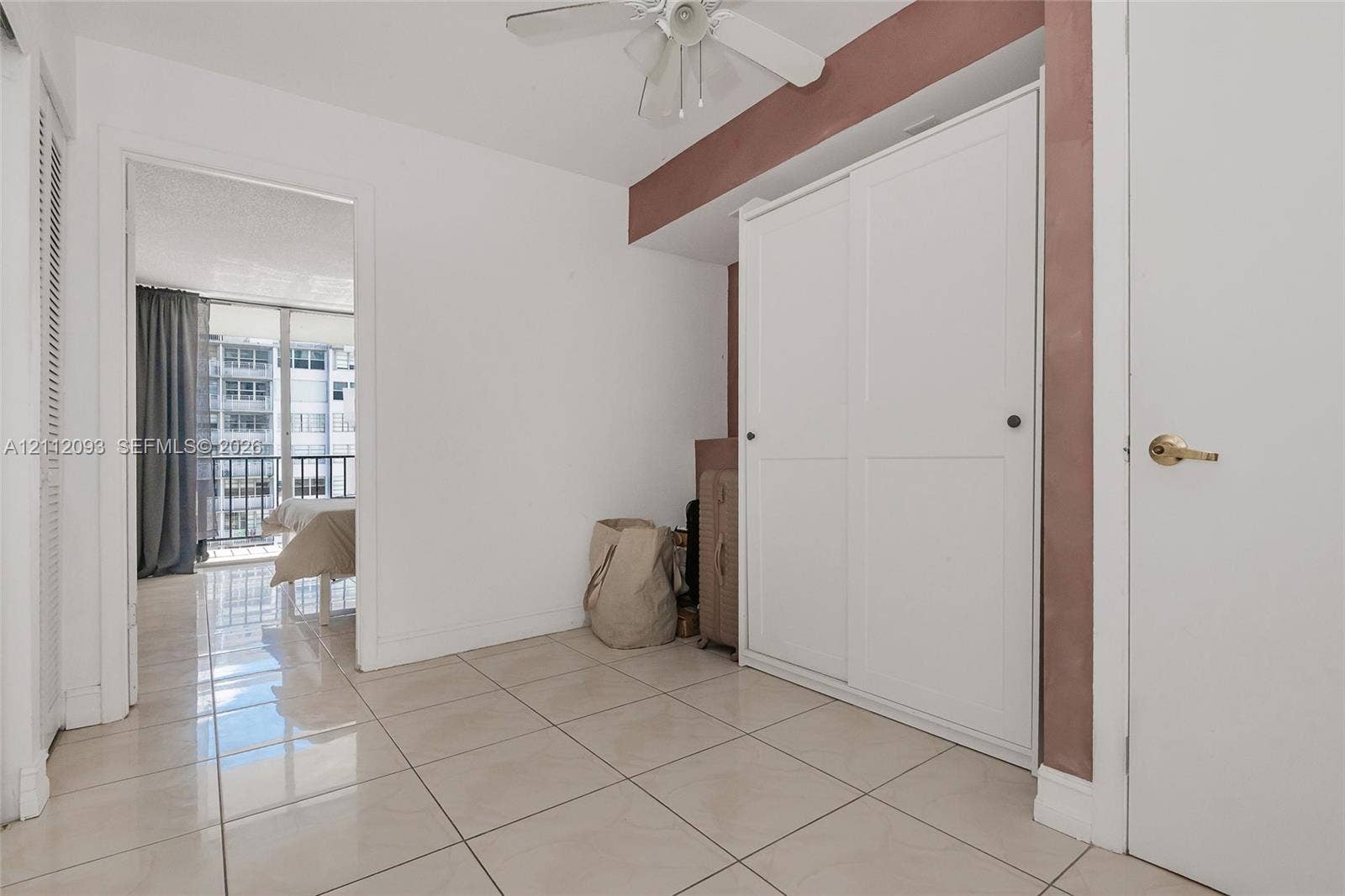 2750 NE 183rd Street, #1612, Aventura, FL 33160 Room featuring large-format ceramic tile flooring, built-in dual-panel sliding closet, and ceiling-mounted fan with light fixture