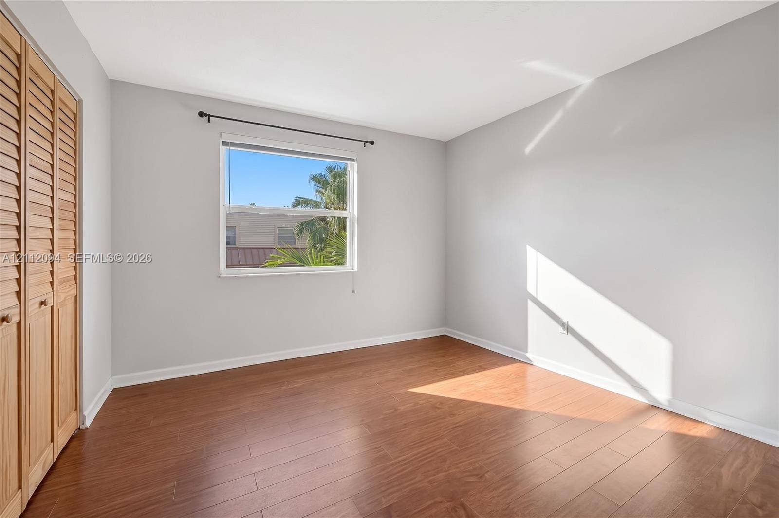 4600 SW 67th Avenue, #242, Miami, Miami, FL 33155 Room featuring wood-finish flooring, neutral wall paint, and a built-in closet with louvered wood doors