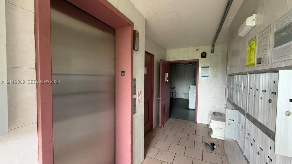 256 Fanshaw G, #2560, Boca Raton, FL 33434 Stainless steel elevator with a pink-toned frame, tiled flooring, and a wall-mounted bank of secure metal mailboxes