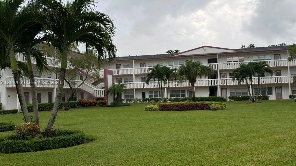256 Fanshaw G, #2560, Boca Raton, FL 33434 Multi-story exterior featuring white balustrade balconies, expansive manicured lawn, and mature palm trees