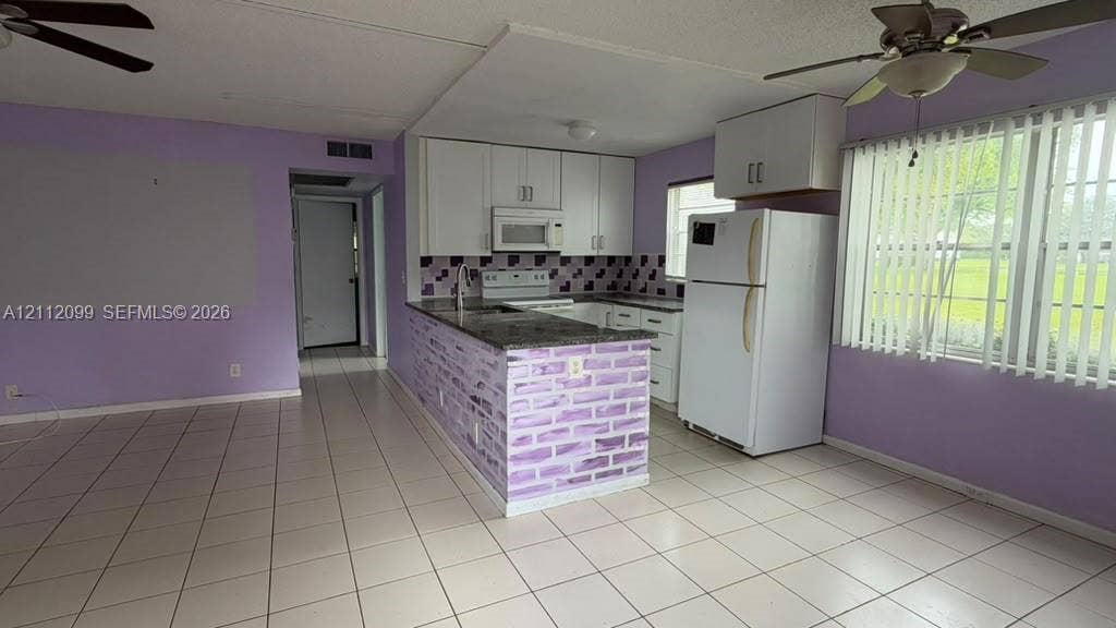 256 Fanshaw G, #2560, Boca Raton, FL 33434 Kitchen featuring white cabinetry, stone-finish countertops, tile backsplash, built-in microwave, and tile flooring