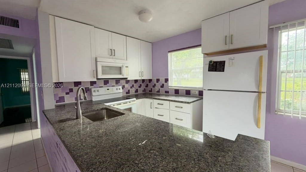 256 Fanshaw G, #2560, Boca Raton, FL 33434 Kitchen featuring white shaker-style cabinetry, stone-finish countertops, an undermount stainless steel sink with a high-arch faucet, a mosaic tile backsplash, and white major appliances