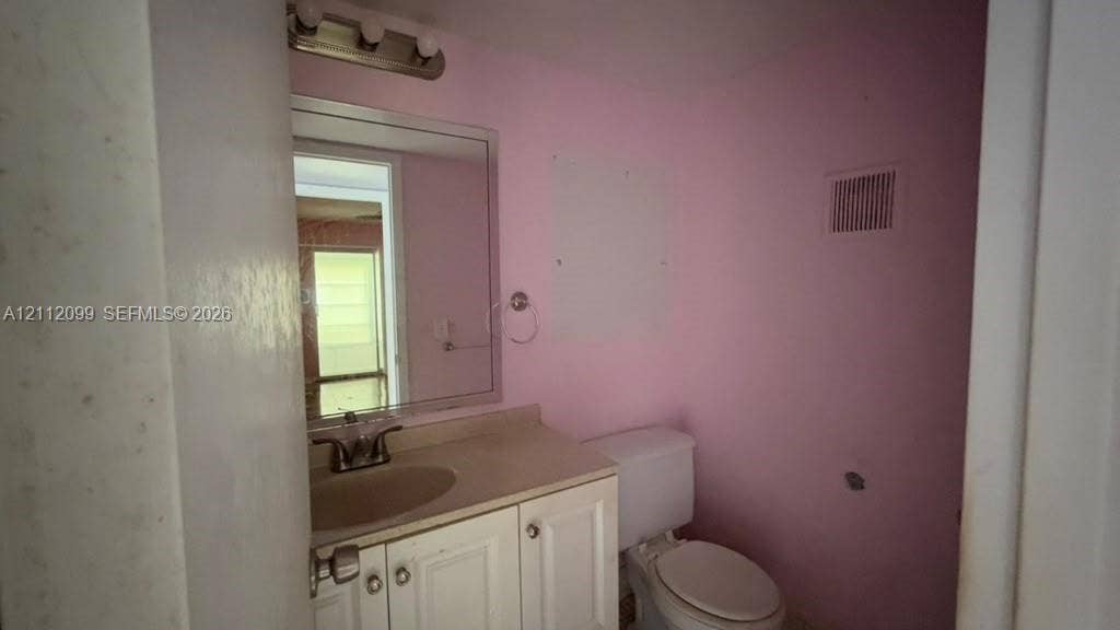 256 Fanshaw G, #2560, Boca Raton, FL 33434 Bathroom featuring a white vanity cabinet with an integrated basin, a polished chrome faucet, a rectangular wall-mounted mirror, and a three-light vanity fixture