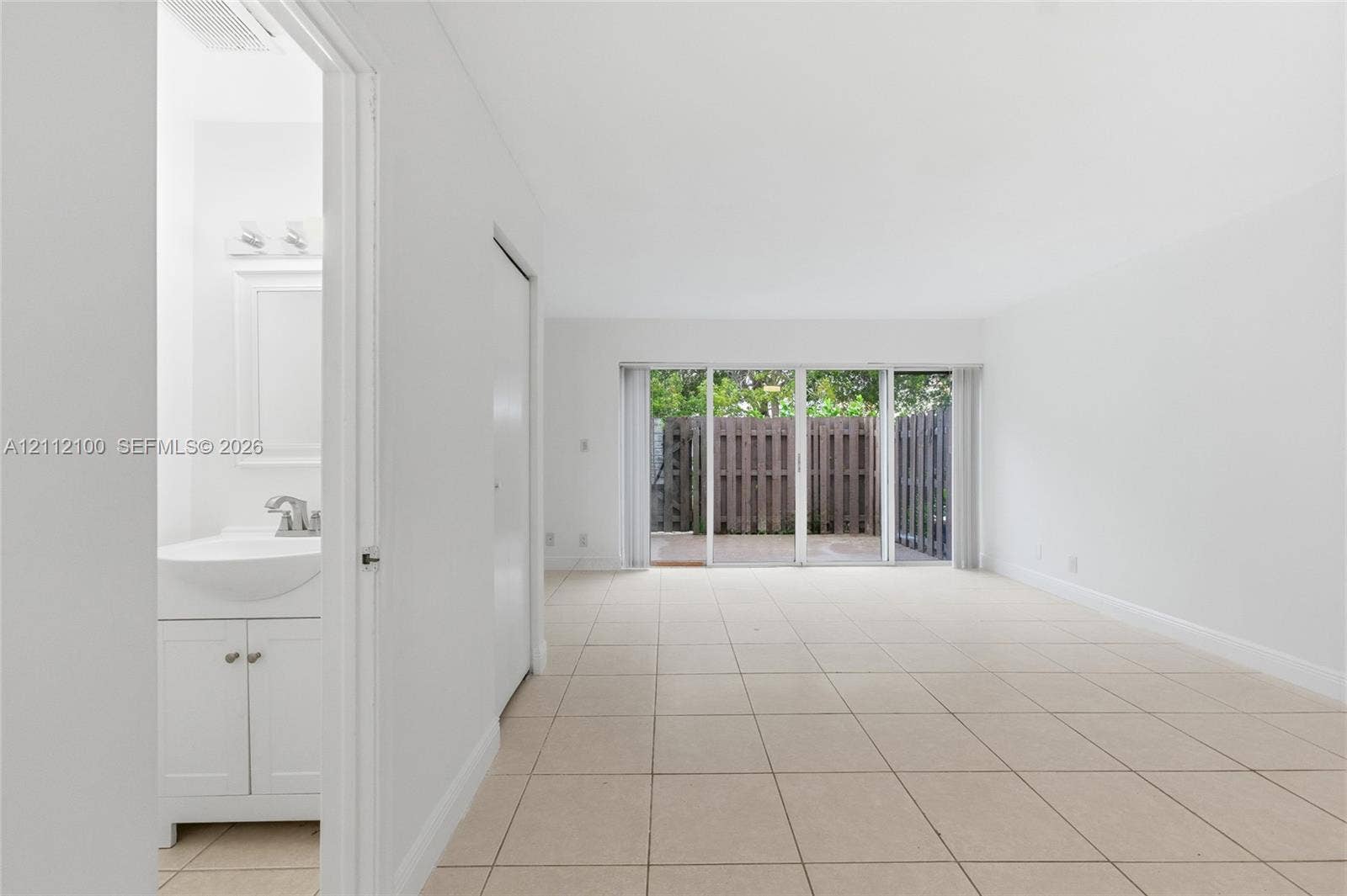 3003 NW 5th Terrace, #1, Pompano Beach, Pompano Beach, FL 33064 Interior featuring neutral ceramic tile flooring, sliding glass doors, and a bathroom vanity with a basin sink and integrated cabinet storage