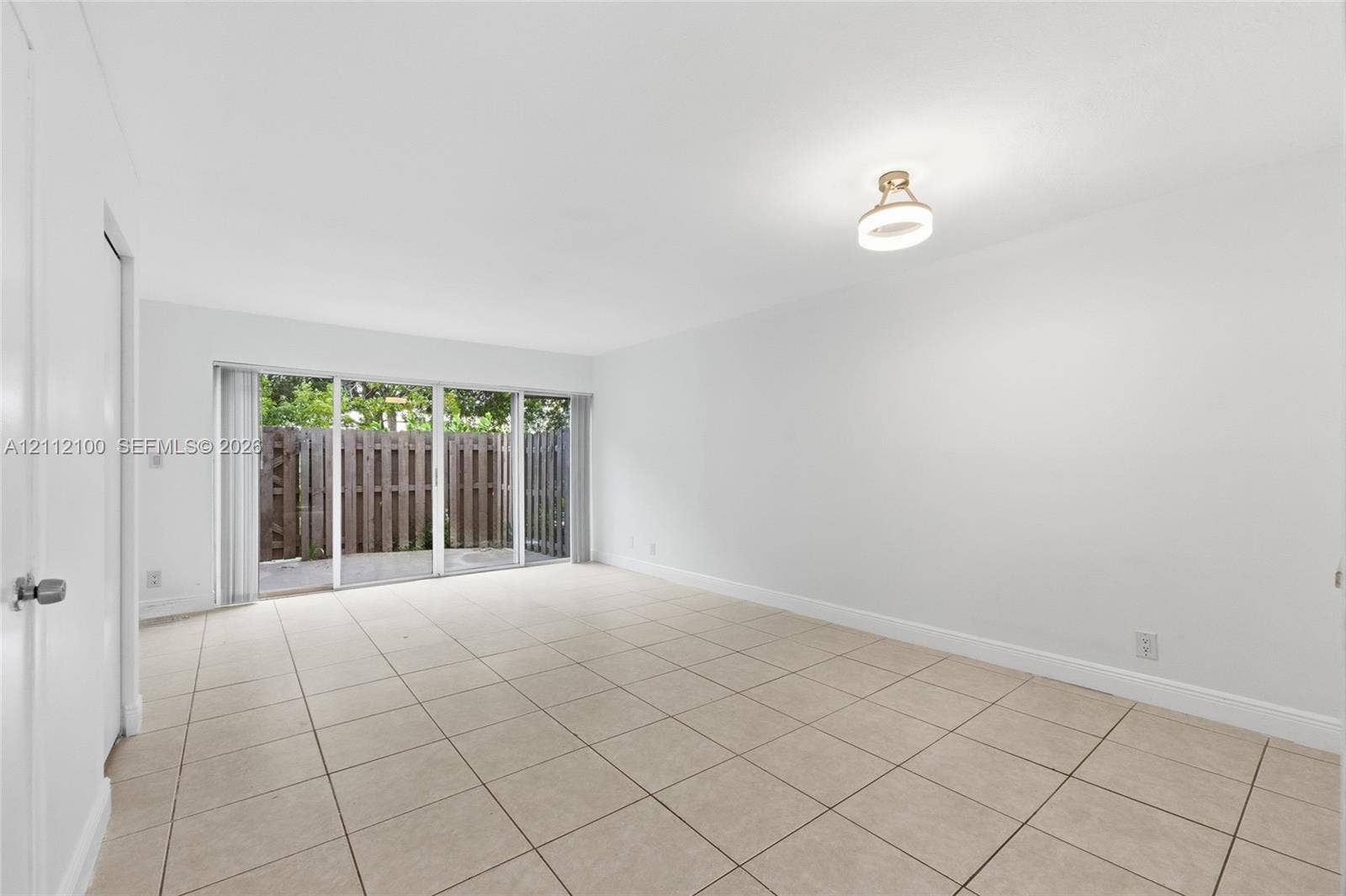 3003 NW 5th Terrace, #1, Pompano Beach, Pompano Beach, FL 33064 Neutral-toned tile flooring, flush-mount circular ceiling lighting, and expansive floor-to-ceiling glass sliding doors opening to a fenced exterior area