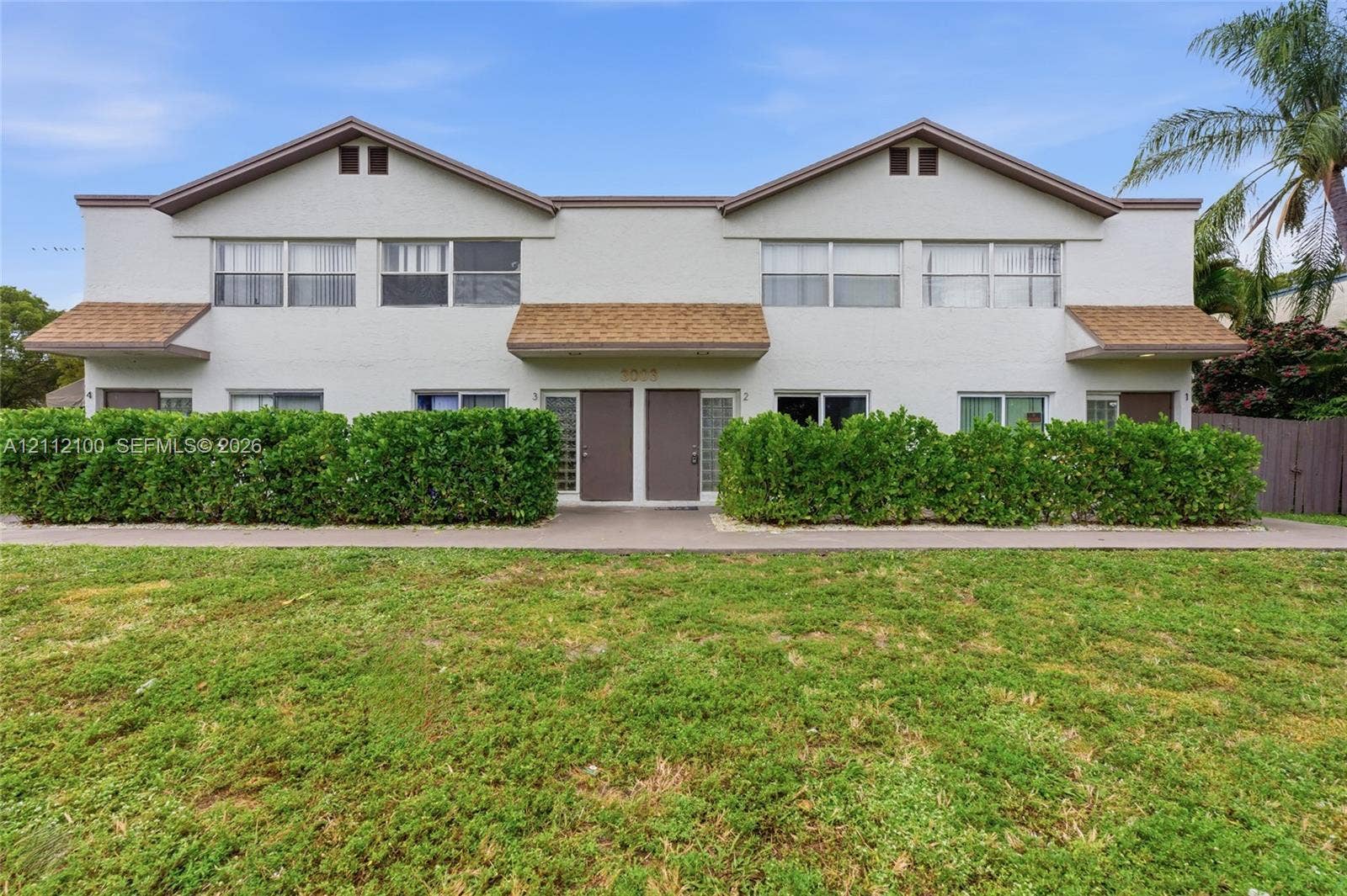 3003 NW 5th Terrace, #1, Pompano Beach, Pompano Beach, FL 33064 Two-story multi-unit exterior featuring stucco siding, gabled roof lines, shingle accents, horizontal sliding windows, and a concrete walkway