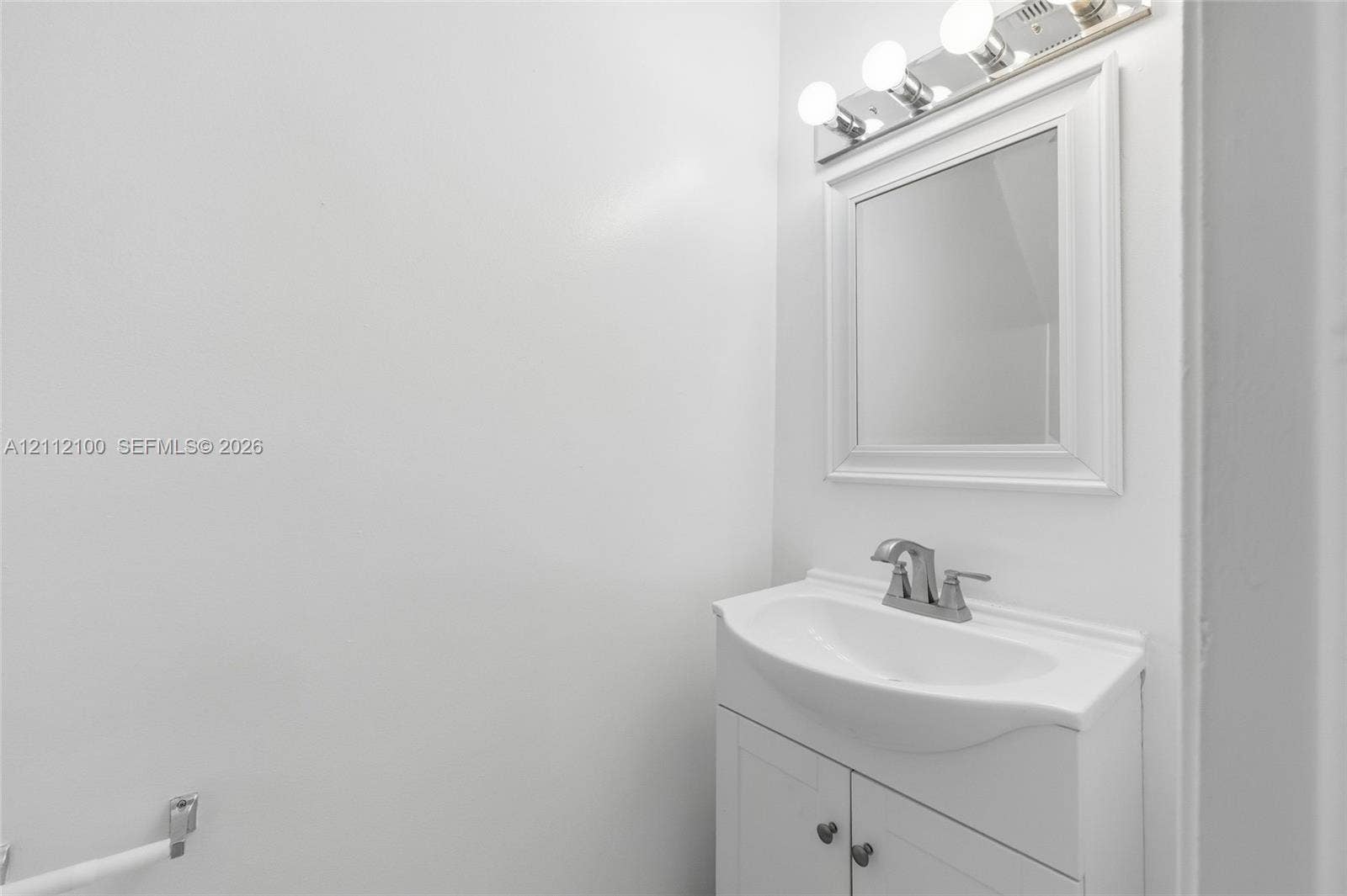 3003 NW 5th Terrace, #1, Pompano Beach, Pompano Beach, FL 33064 White vanity with an integrated sink, polished metal faucet, matching framed mirror, and multi-bulb vanity light fixture