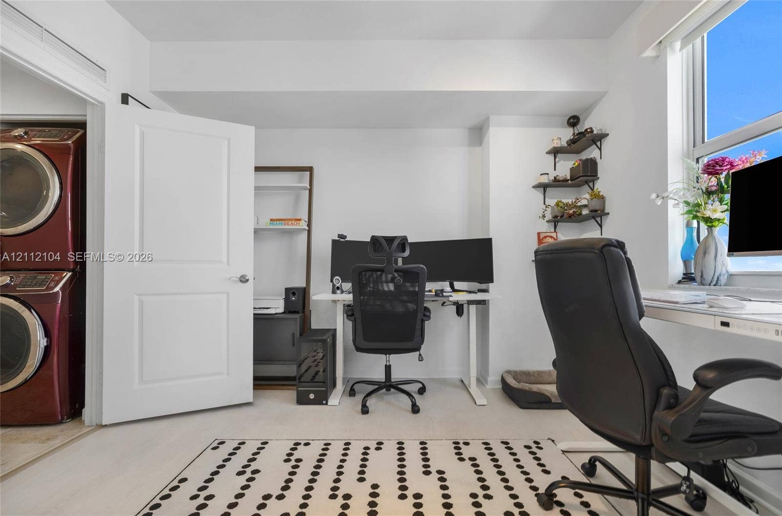 7900 Harbor Island Drive, #1203, North Bay Village, North Bay Village, FL 33141 Room featuring neutral wall-to-wall carpeting, a large window, wall-mounted tiered shelving, and an enclosed laundry closet with stacked washer and dryer unit