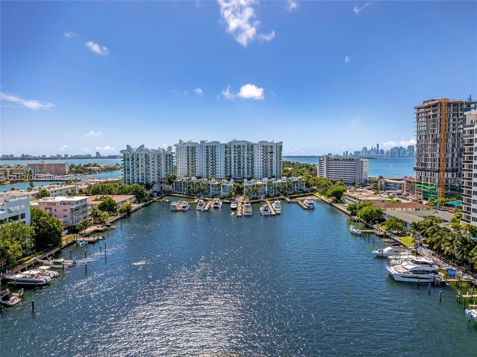 7900 Harbor Island Drive, #1203, North Bay Village, North Bay Village, FL 33141 Aerial waterway perspective featuring a deep-water canal, private marina slips, coastal residential buildings, and distant urban skyline