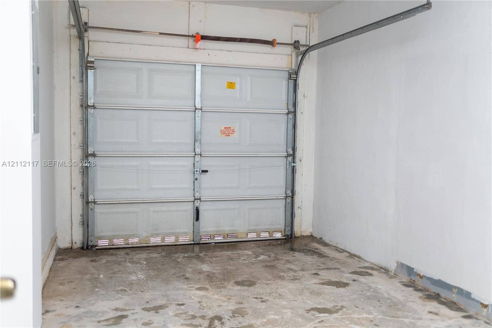 1209 NE 32nd Avenue, Homestead, Homestead, FL 33033 Enclosed garage space featuring a paneled sectional door, overhead tracks, and concrete flooring