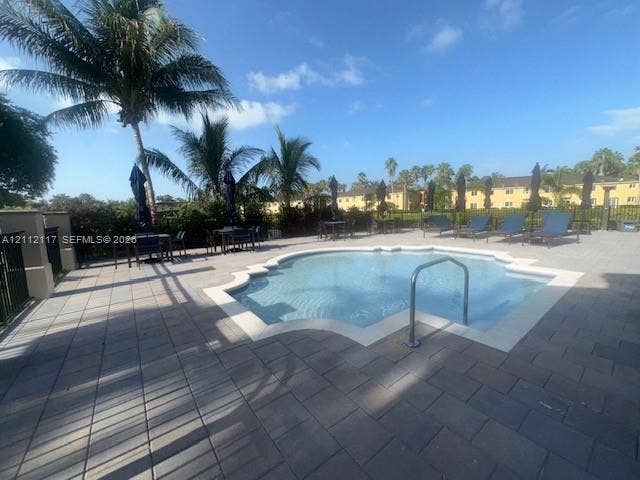 1209 NE 32nd Avenue, Homestead, Homestead, FL 33033 Swimming pool featuring a concrete paver deck, metal pool ladder, and surrounding palm trees