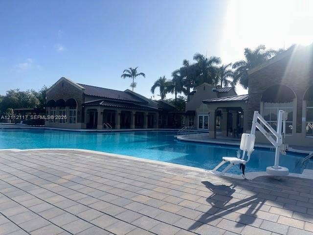 1209 NE 32nd Avenue, Homestead, Homestead, FL 33033 Large outdoor swimming pool featuring paver stone decking, covered patio areas, and structural masonry exteriors