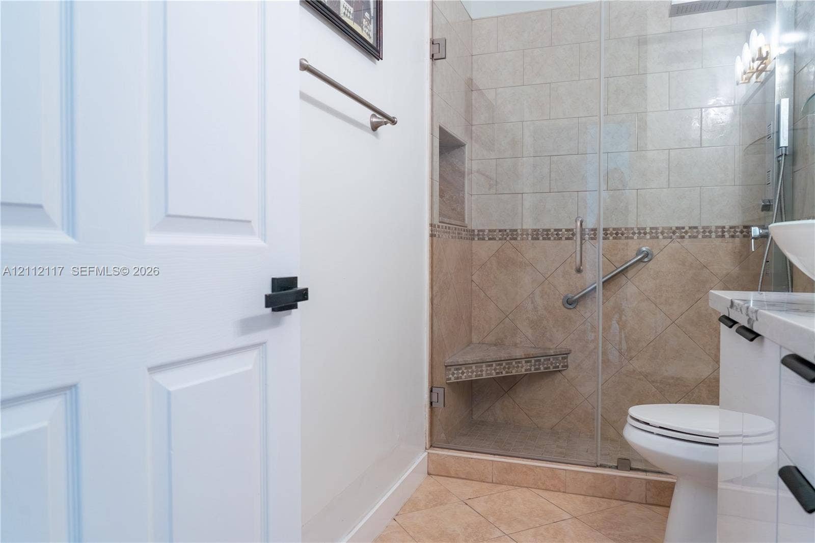 1209 NE 32nd Avenue, Homestead, Homestead, FL 33033 Walk-in shower with frameless glass door, tile surround, built-in corner bench, and recessed wall niche, paired with a white vanity featuring a stone countertop and rectangular vessel sink