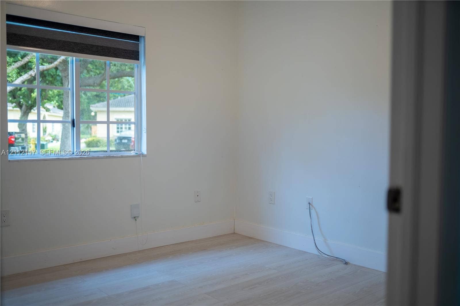 1209 NE 32nd Avenue, Homestead, Homestead, FL 33033 Neutral-toned interior room featuring wood-finish flooring and a multi-pane window with a roller shade