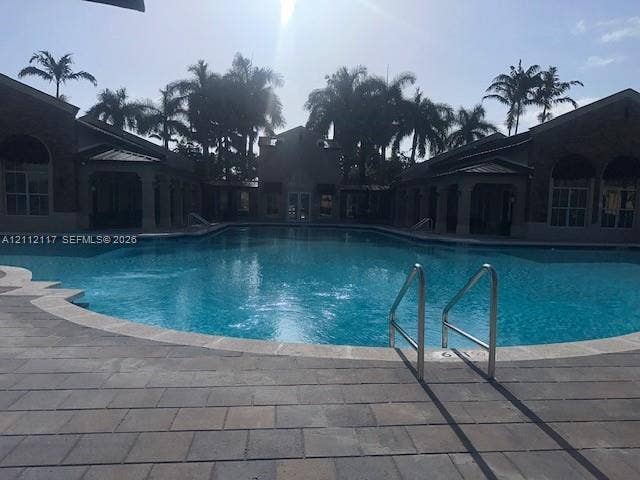 1209 NE 32nd Avenue, Homestead, Homestead, FL 33033 In-ground swimming pool featuring stone paver decking, metal railings, and an expansive courtyard surrounded by palm trees