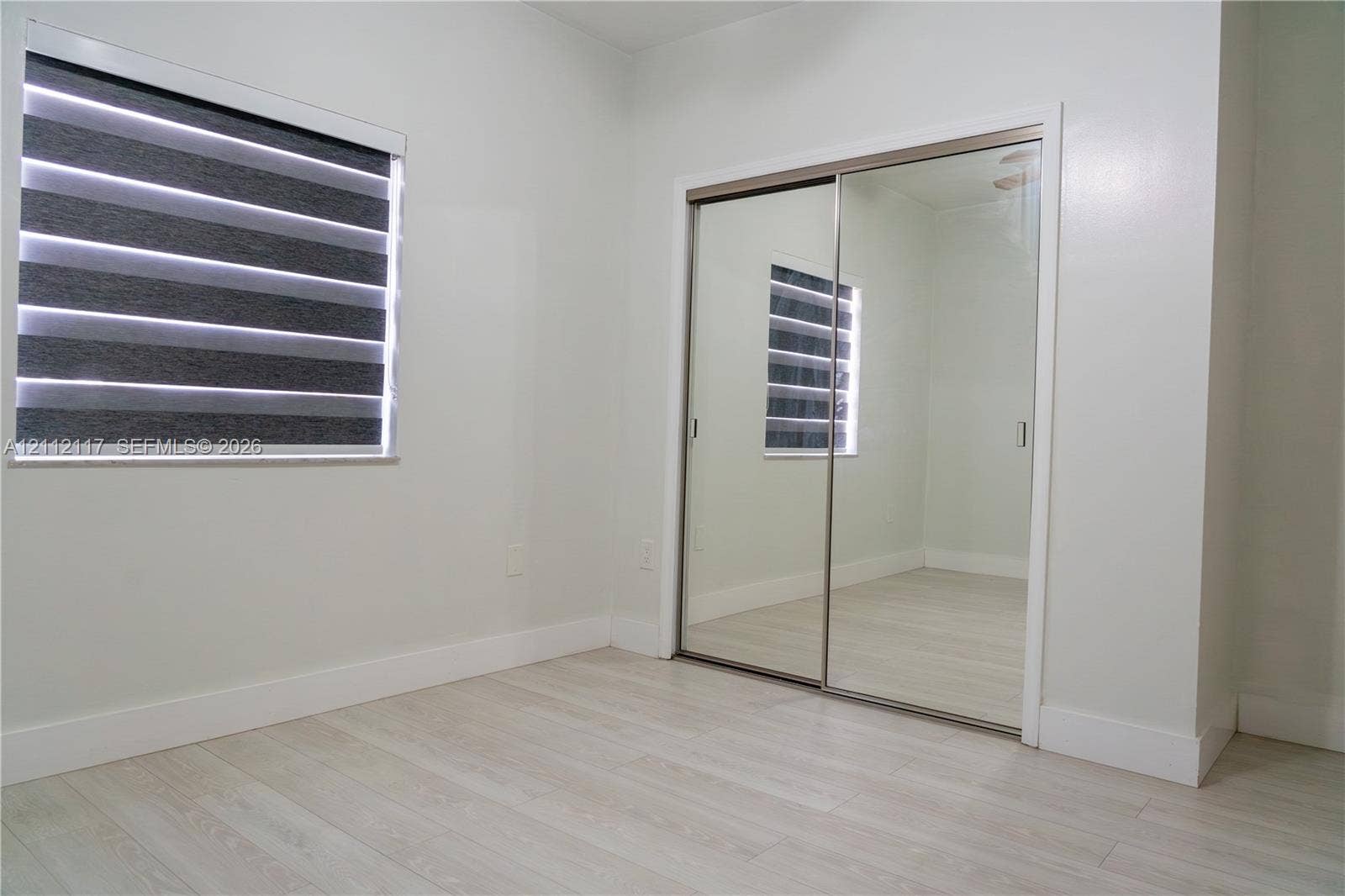 1209 NE 32nd Avenue, Homestead, Homestead, FL 33033 Light-toned wood-finish flooring, dual-panel mirrored sliding closet doors, and multi-layered fabric window blinds