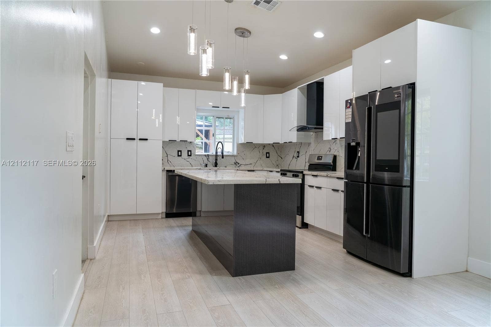 1209 NE 32nd Avenue, Homestead, Homestead, FL 33033 Kitchen featuring high-gloss white cabinetry, a center island with a dark finish, stone-patterned countertops, a stainless steel appliance package, and modern glass pendant lighting