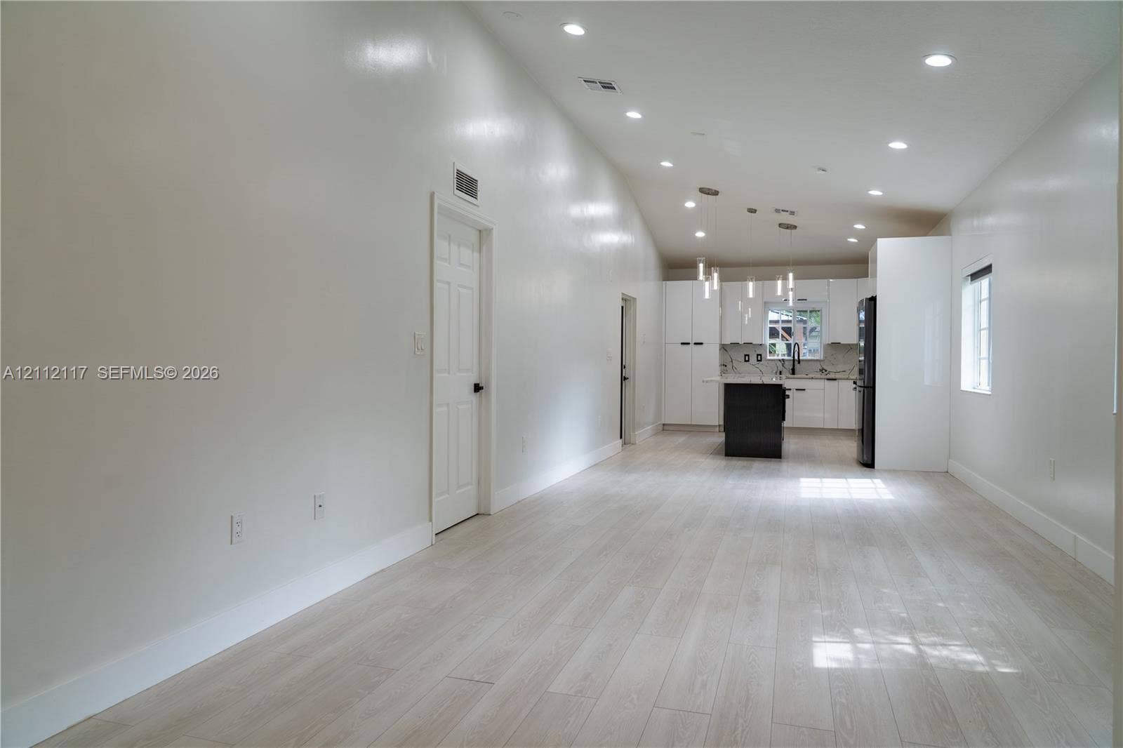 1209 NE 32nd Avenue, Homestead, Homestead, FL 33033 Vaulted ceilings, wood-finish flooring, recessed lighting, white cabinetry, and kitchen island