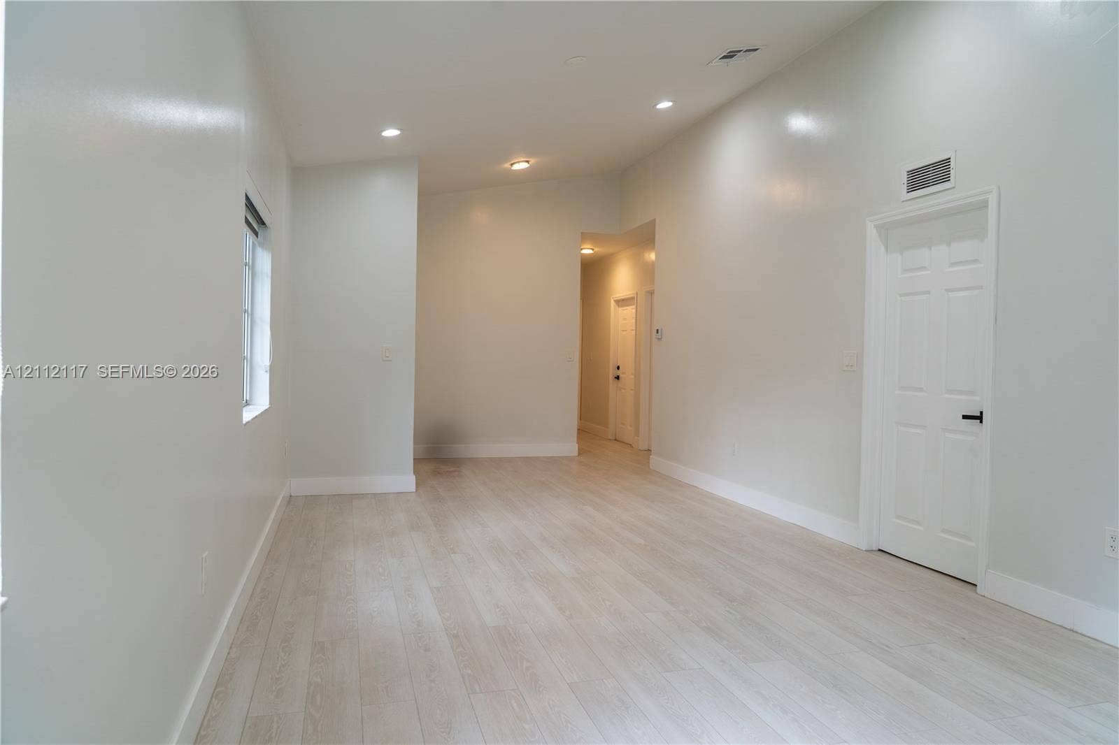 1209 NE 32nd Avenue, Homestead, Homestead, FL 33033 Interior space featuring vaulted ceilings, wood-finish flooring, recessed lighting, and a six-panel door with matte black hardware