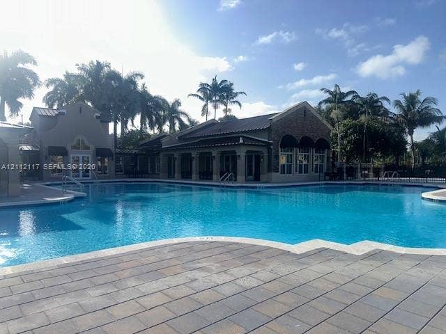 1209 NE 32nd Avenue, Homestead, Homestead, FL 33033 Large swimming pool featuring stone-paver decking, metal roof architecture, stone veneer accents, and covered poolside lounging areas