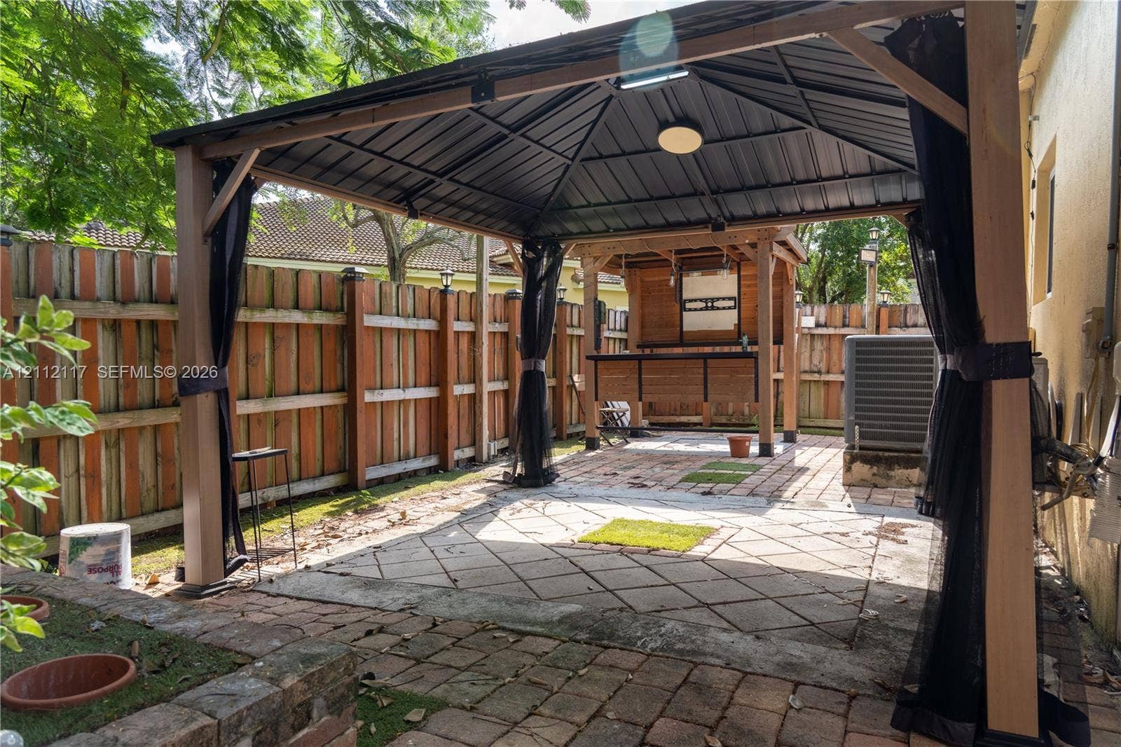 1209 NE 32nd Avenue, Homestead, Homestead, FL 33033 Covered outdoor structure with a metal roof, wood-frame bar, paver patio, and privacy fencing