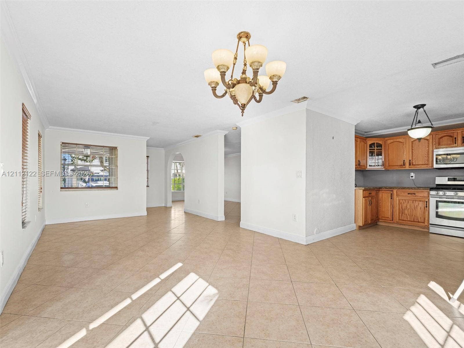 13990 SW 161st Terrace, Miami, FL 33177 Open-concept interior featuring tile flooring, crown molding, arched entryways, a multi-arm chandelier, and built-in wood cabinetry