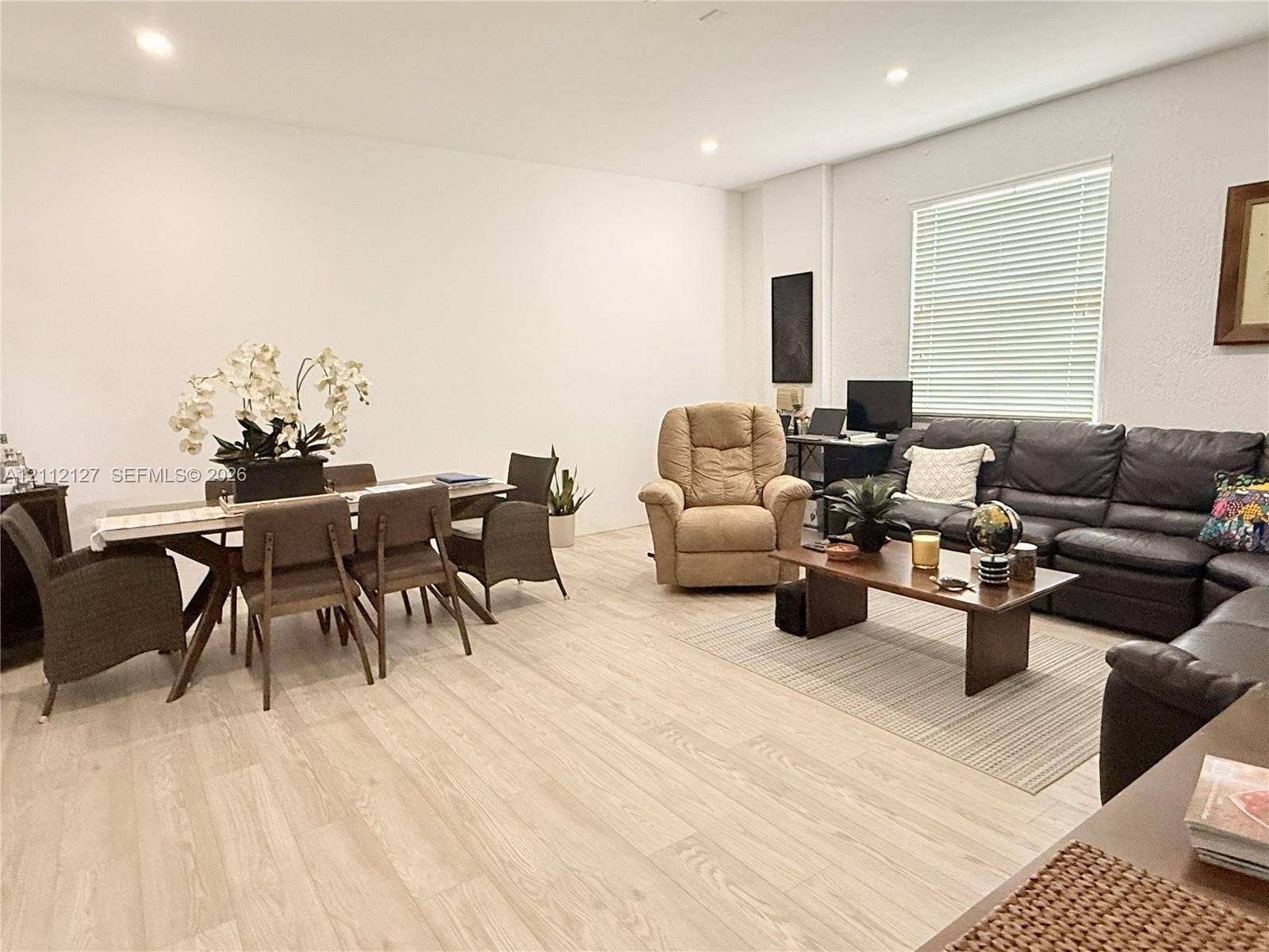 Light-toned wood-finish flooring, recessed lighting, and large window with blinds