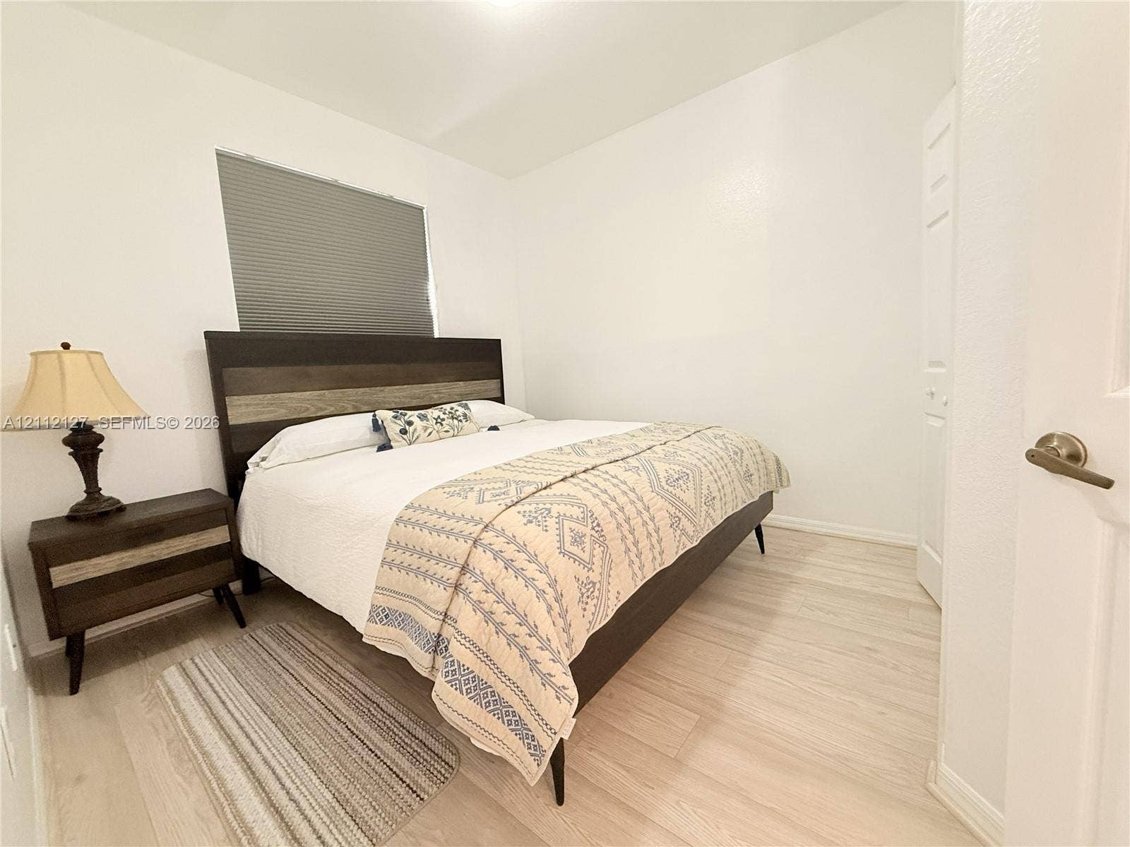 Neutral-toned wall finish, wood-finish flooring, and a window with a fitted cellular shade