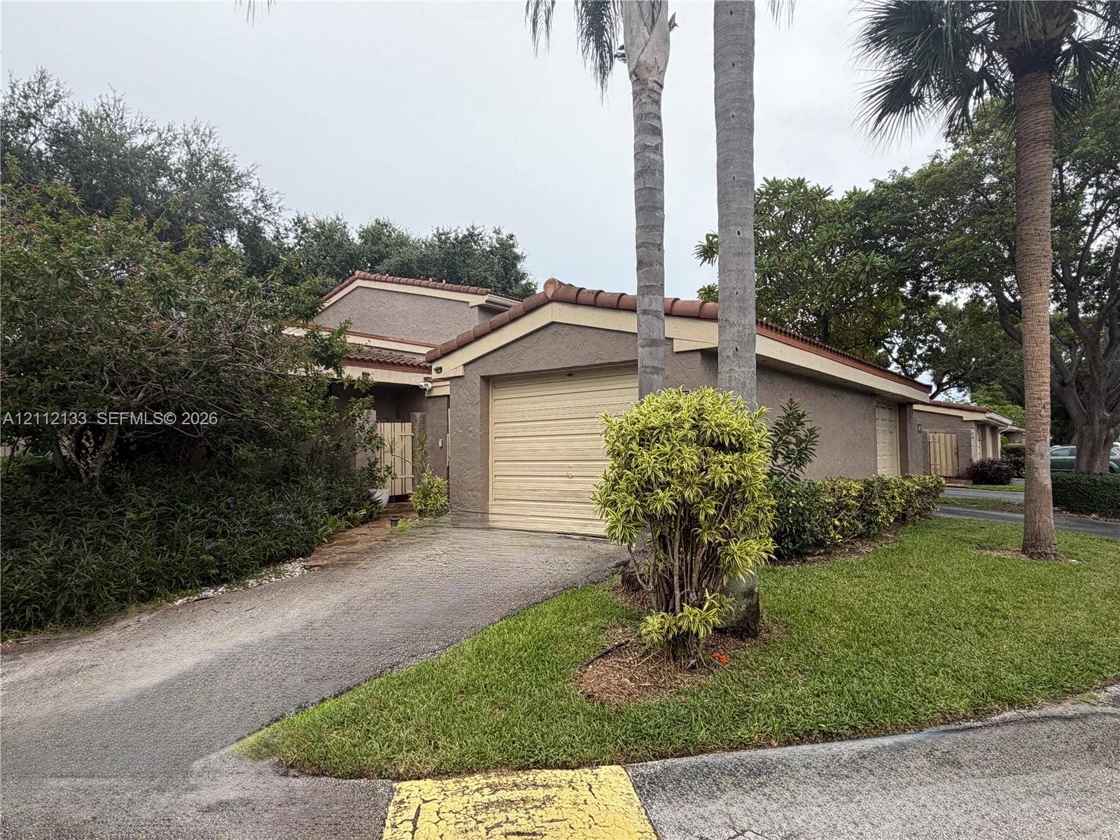 407 Bonnie Brae Way, #22, Hollywood, Hollywood, FL 33021 Stucco exterior featuring a tile roof, an attached garage, and mature palm trees within a landscaped front lawn
