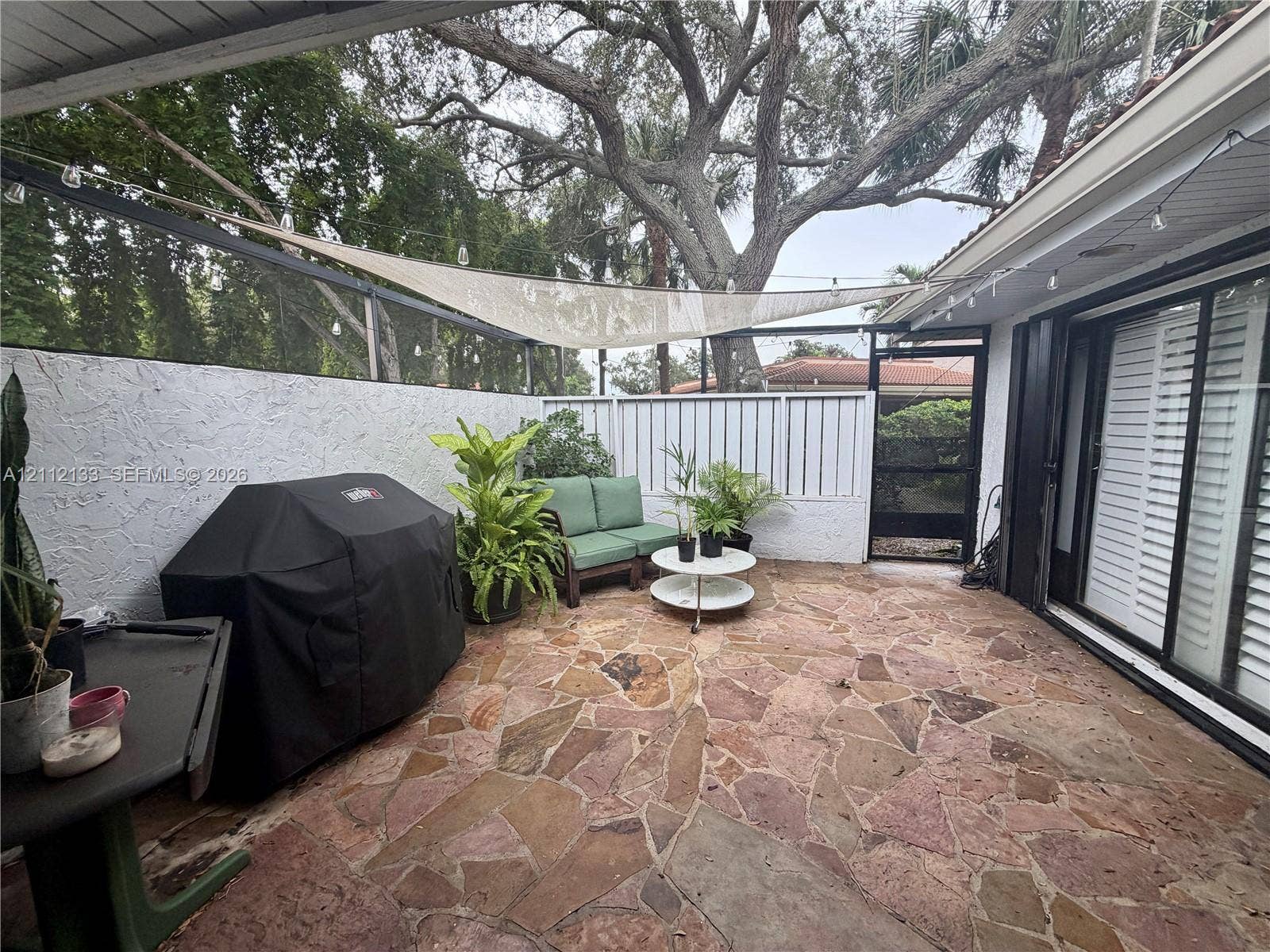 407 Bonnie Brae Way, #22, Hollywood, Hollywood, FL 33021 Screen-enclosed patio featuring flagstone flooring, textured masonry wall, and sliding glass doors