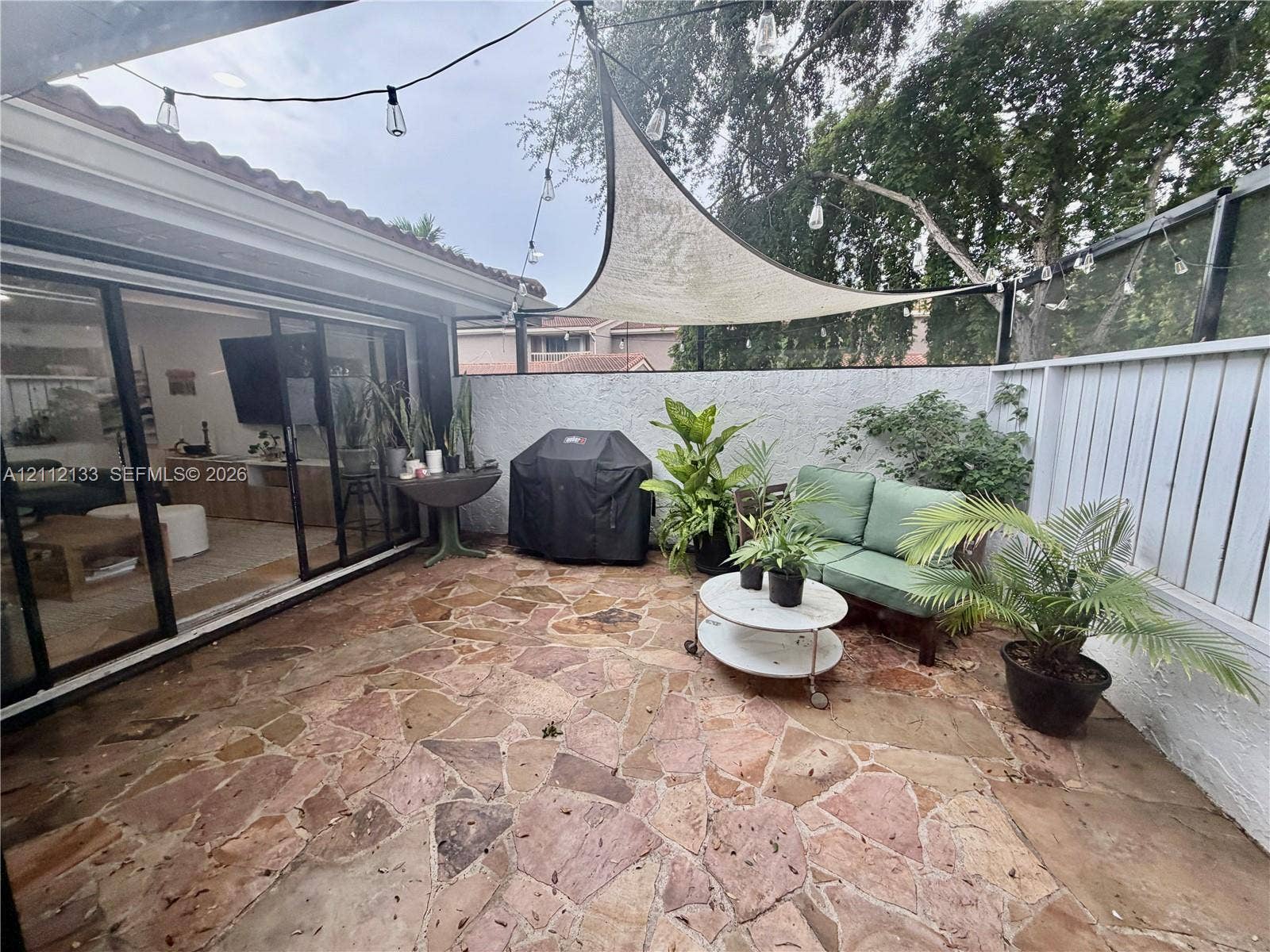407 Bonnie Brae Way, #22, Hollywood, Hollywood, FL 33021 Flagstone patio featuring a white perimeter wall, sliding glass doors, and a suspended triangular shade sail