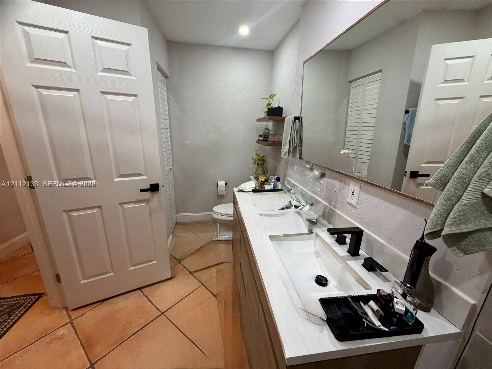 407 Bonnie Brae Way, #22, Hollywood, Hollywood, FL 33021 Dual-sink vanity with matte black fixtures, stone-surface countertop, full-width mirror, and terracotta tile flooring